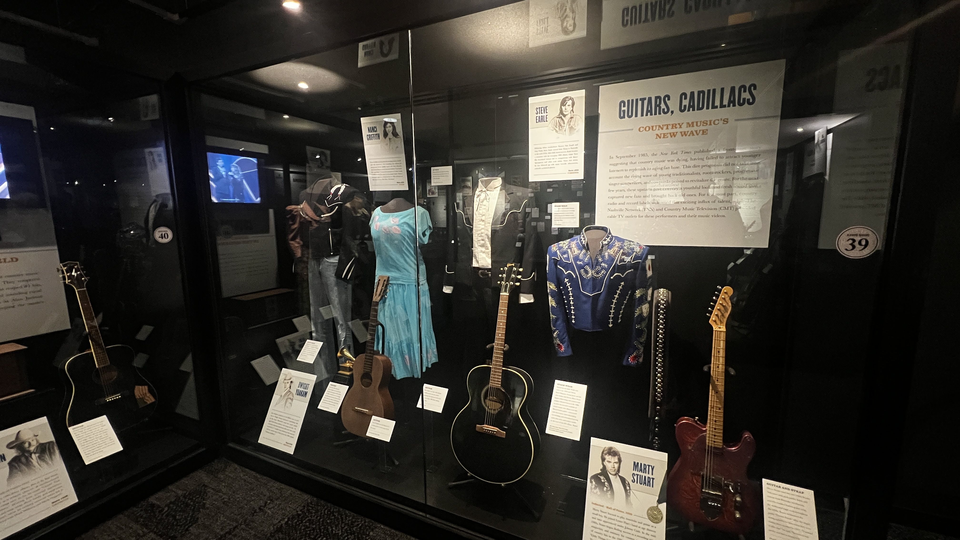 Artifacts, outfits and guitars in a glass case. 