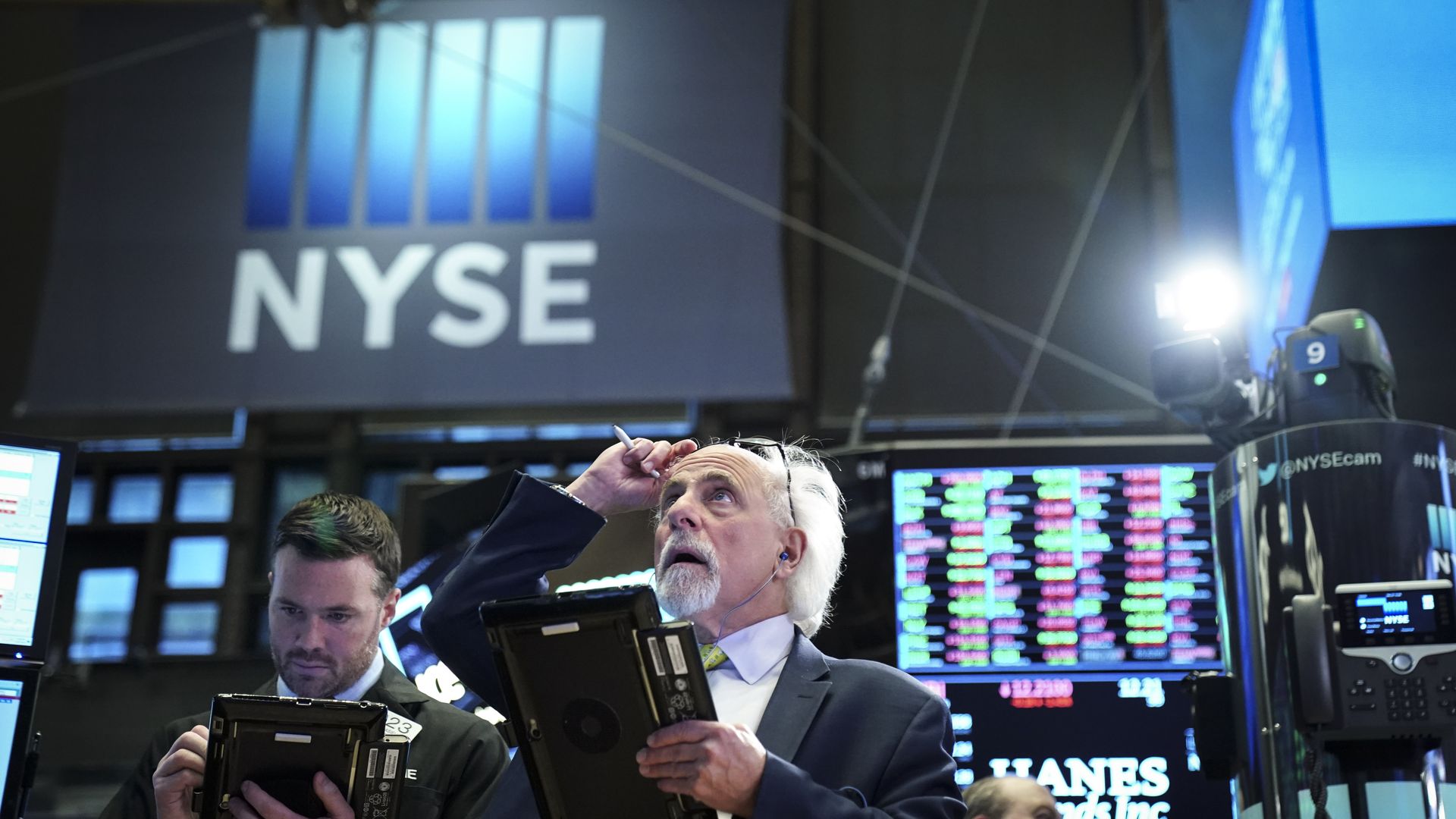 Two traders look at trading screens on NYSE floor.