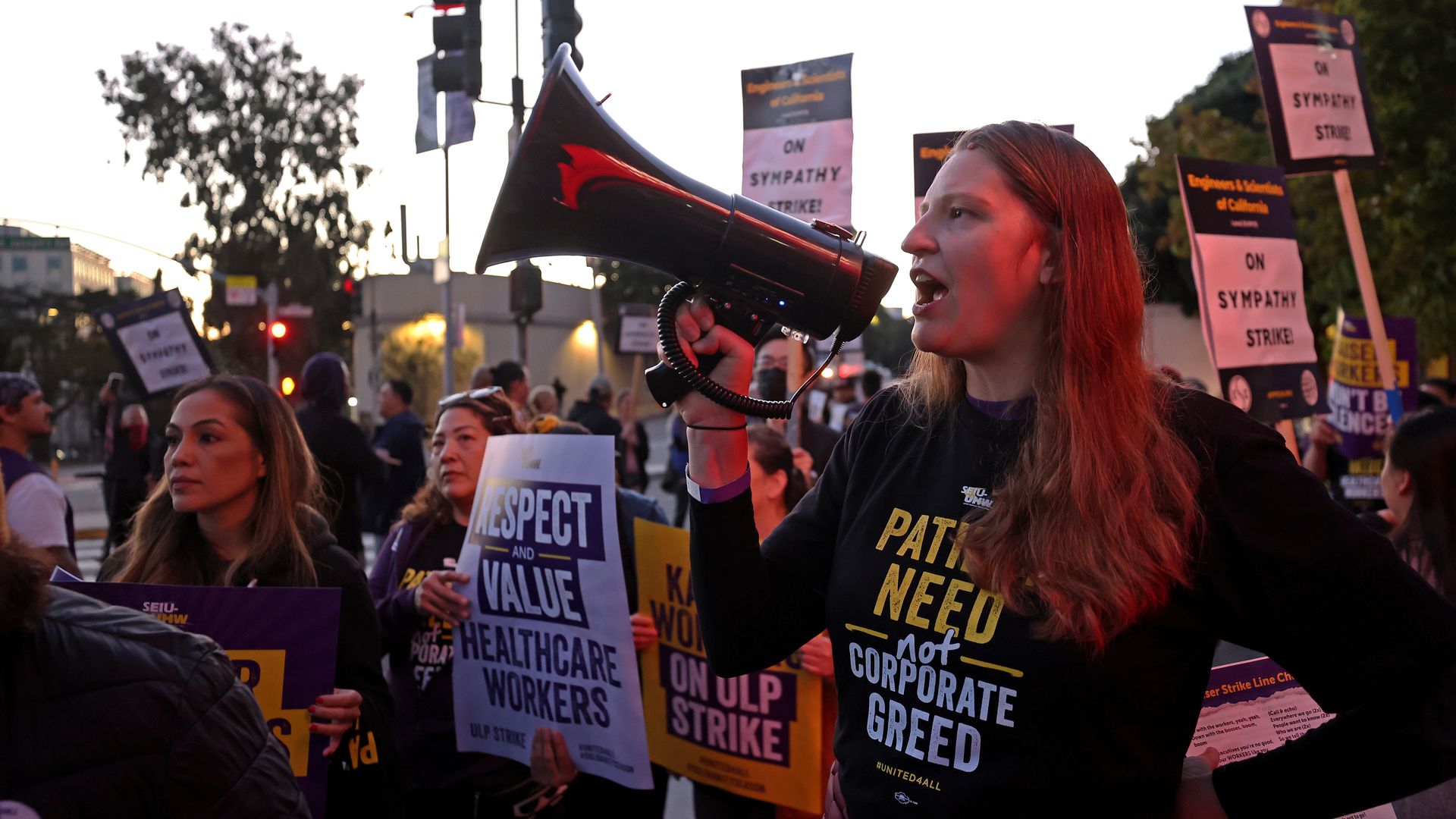 Photo of Kaiser workers holding bullhorns and signs that say "Respect and value health care workers" during a strike