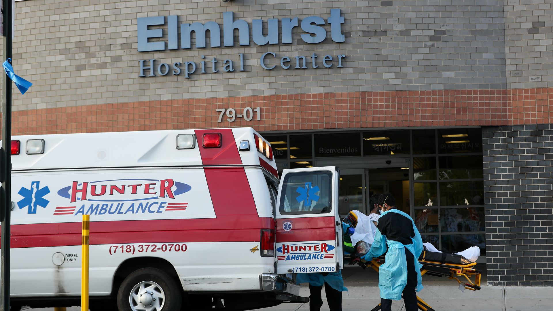 Workers pull a patient out of an ambulance in front of Elmhurst Hospital Center.