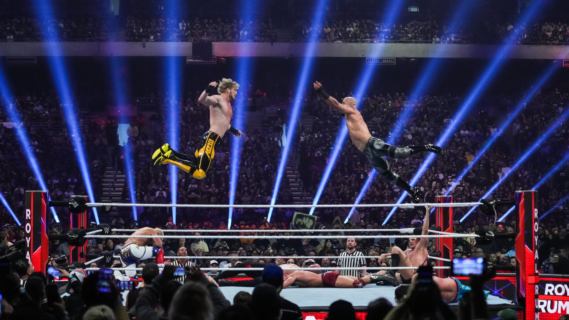 Two WWE superstars fly towards each other in a ring. 