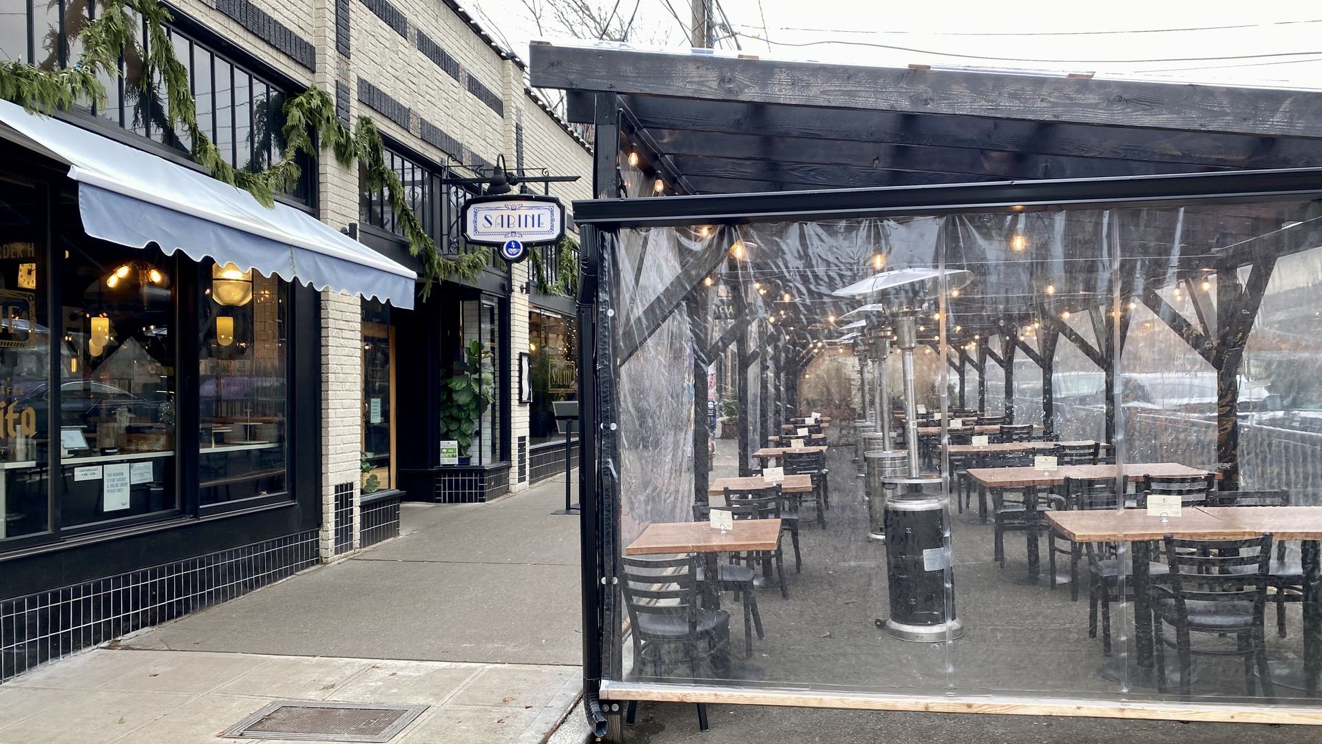 An outdoor seating area on the curb outside a restaurant.