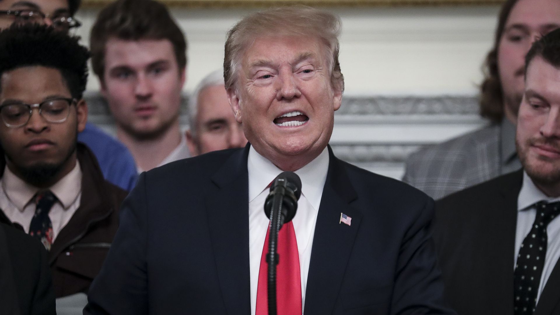 Donald Trump giving a speech, in his customarily long red tie.
