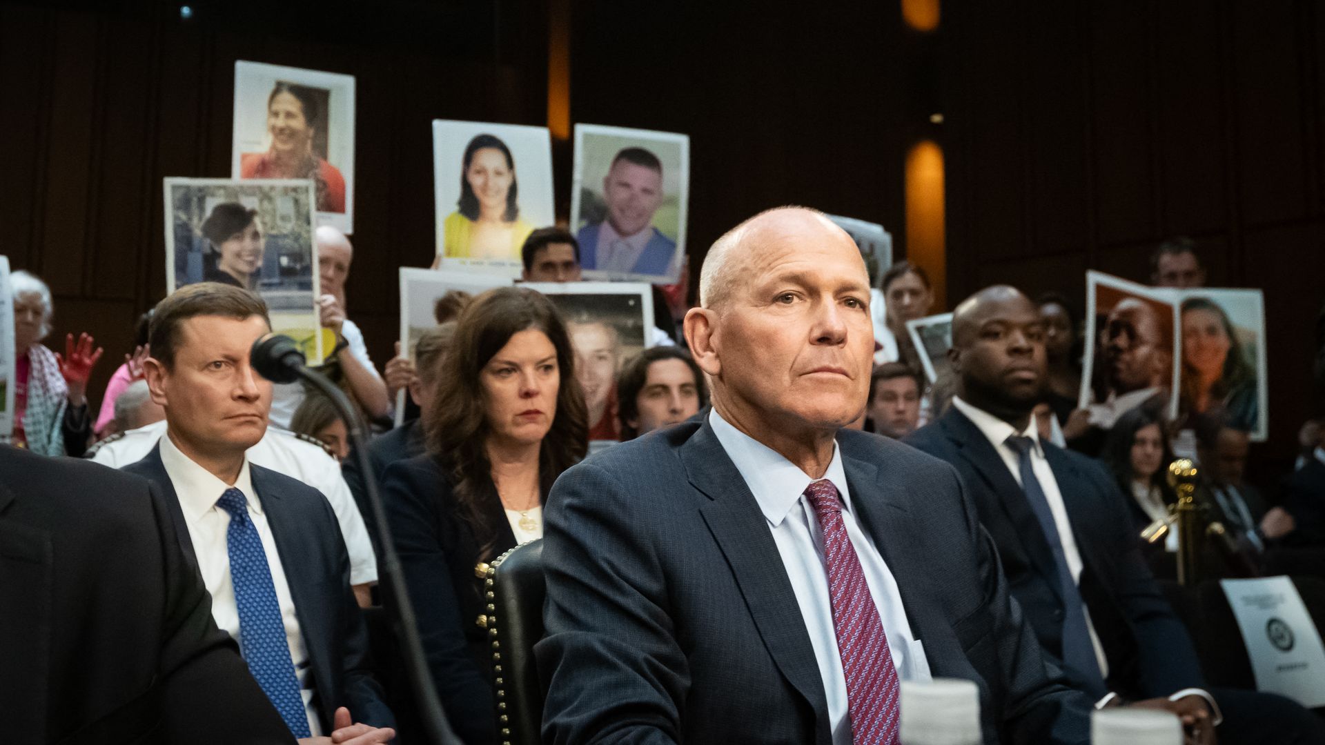 Families of victims of Ethiopian Airlines flight 302, a Boeing 737 Max 8 that crashed in 2019, display photos of their loved ones as Boeing CEO Dave Calhoun testifies before a subcommittee of the Senate Energy and National Resources Committee on the company's safety culture, Washington, DC, June 18,
