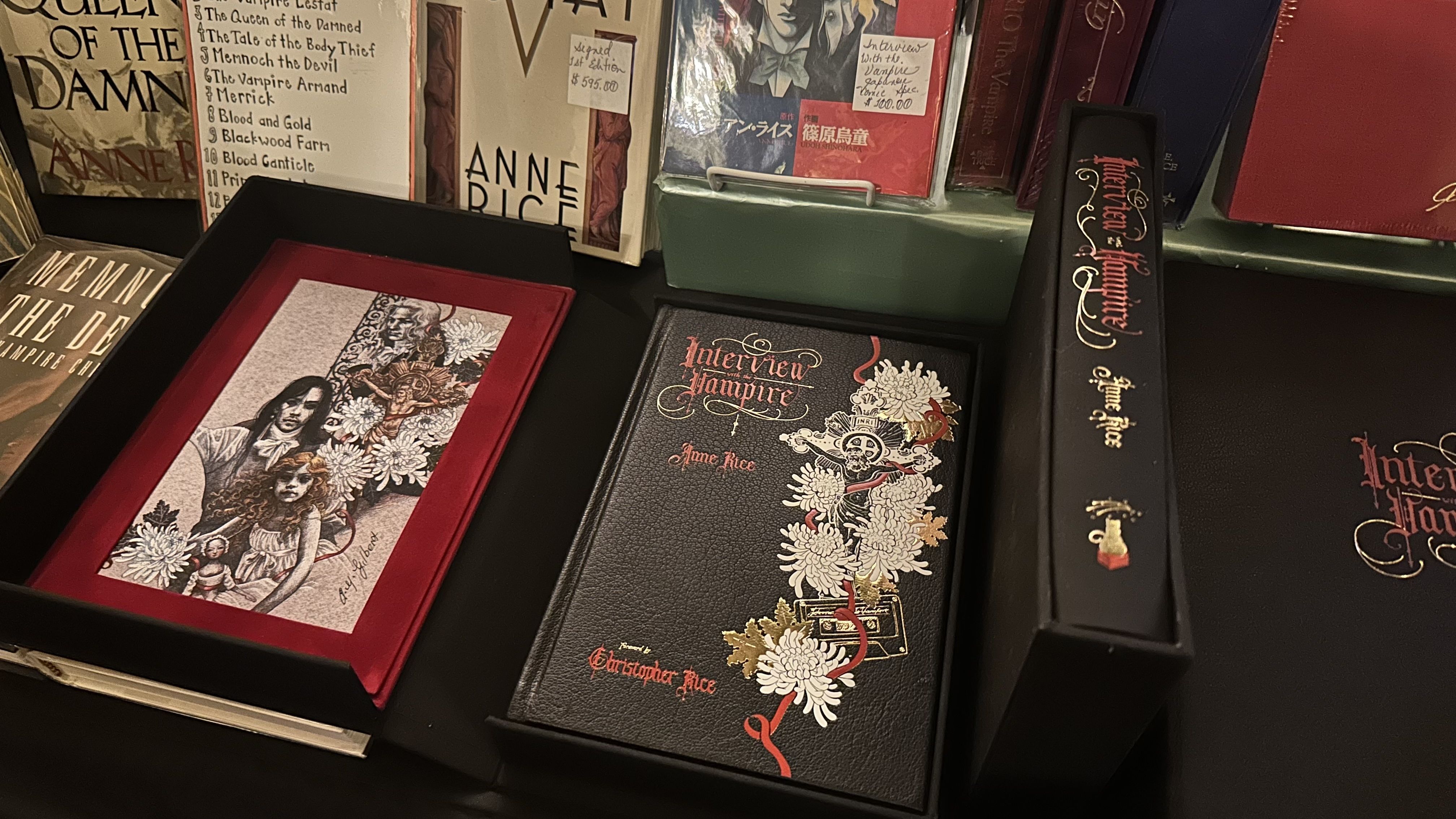 A display of special edition books by Anne Rice, including a black leather-bound "Interview with the Vampire" with red and gold floral and skull designs, alongside other vampire-themed editions.