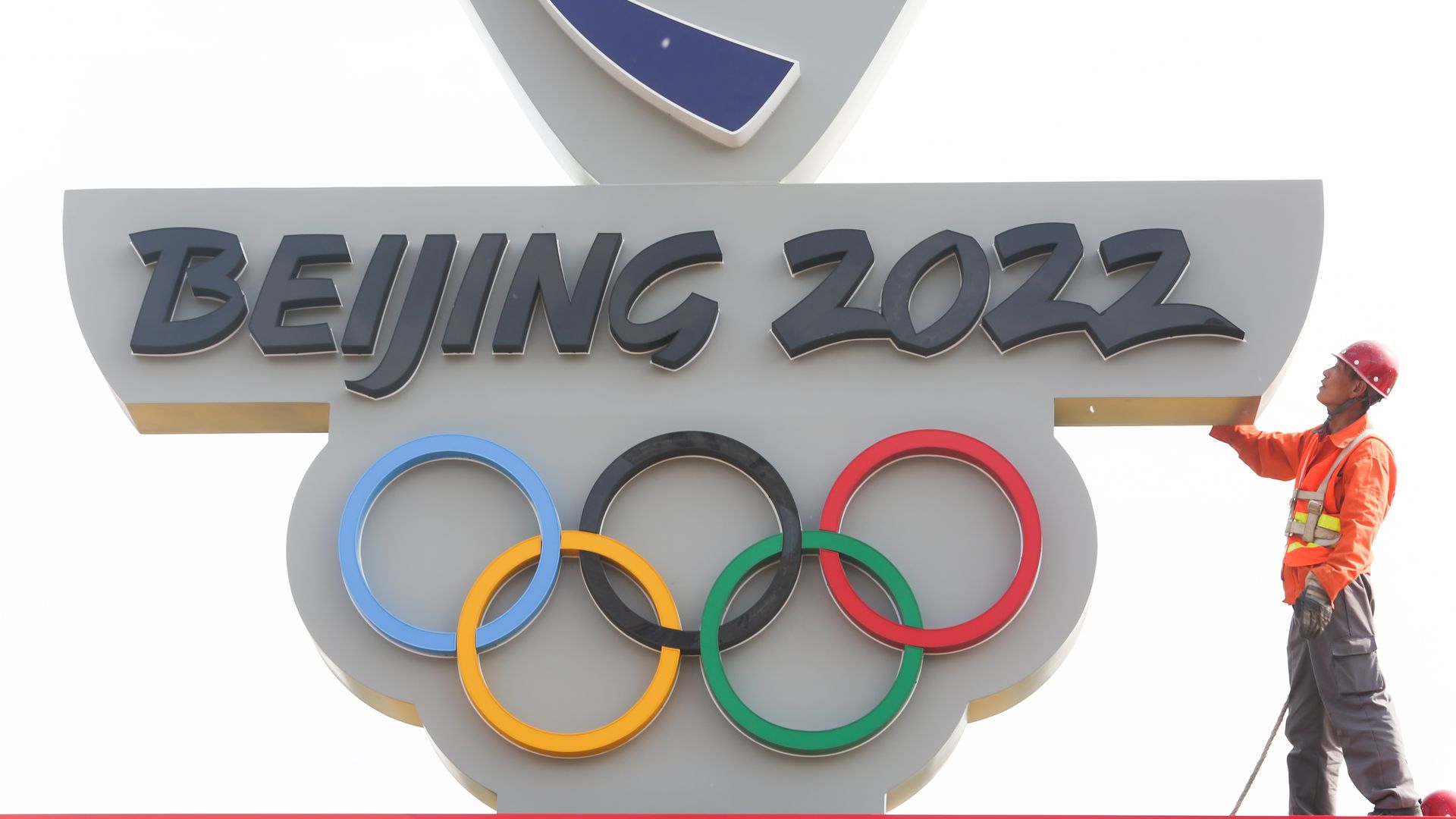 Photo of a countdown board that reads "Beijing 2022" with a construction worker on the side 