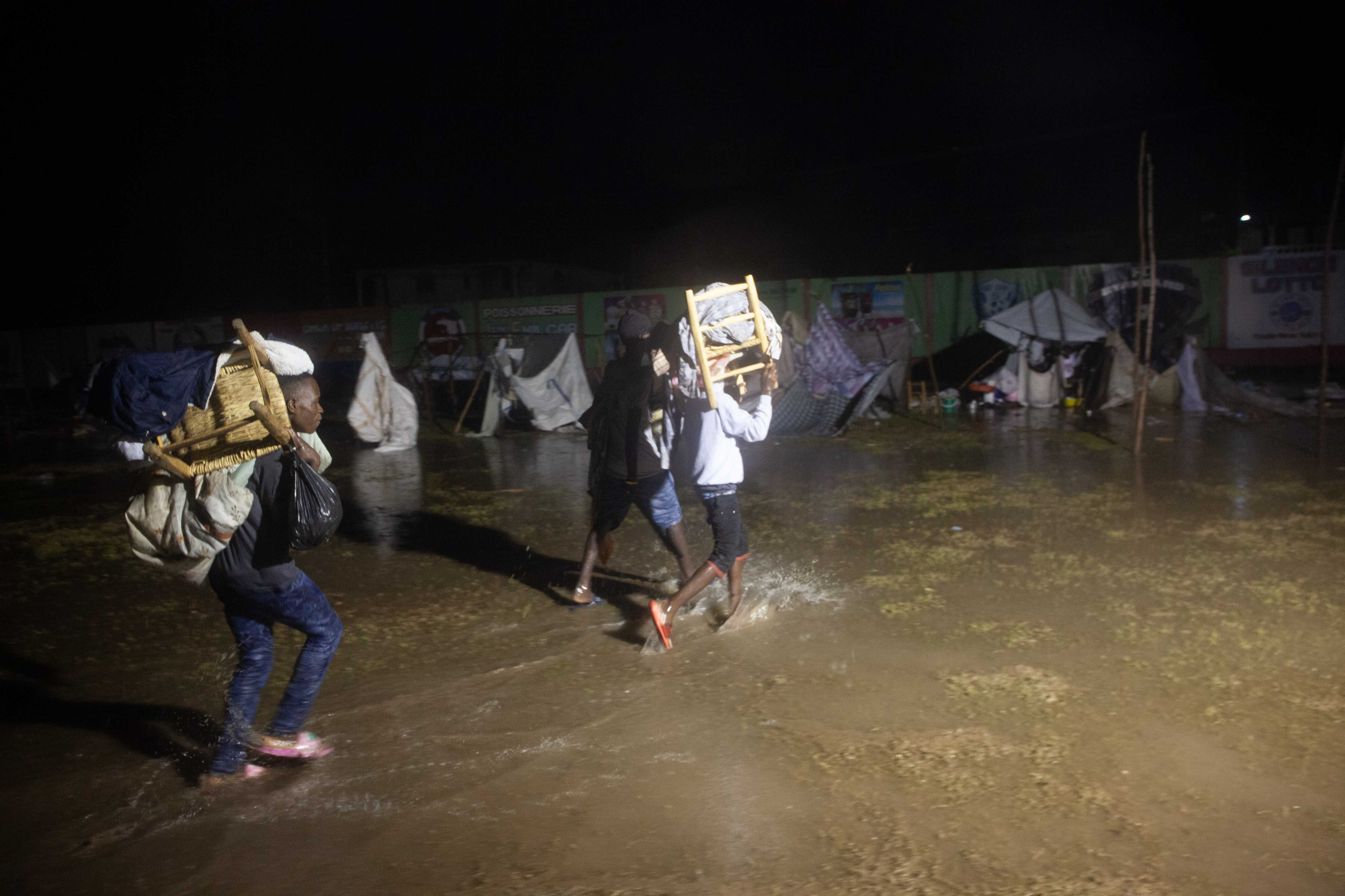 People leave as Tropical Storm Grace hits a refugee camp at a football field called Parc Lande de Gabion after a 7.2-magnitude earthquake struck Haiti on August 16, 2021 in Les Cayes, Haiti.