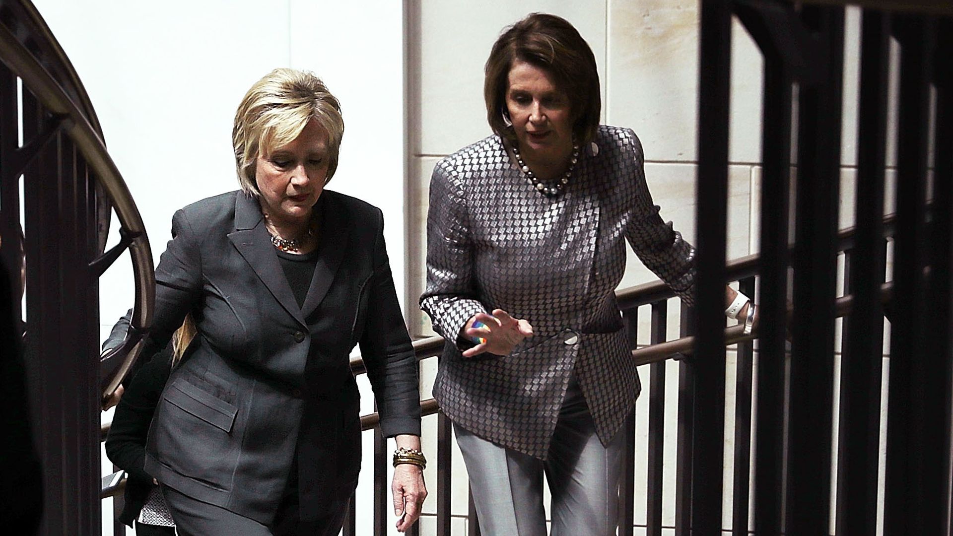 Hillary Clinton and Nancy Pelosi talk together walking.