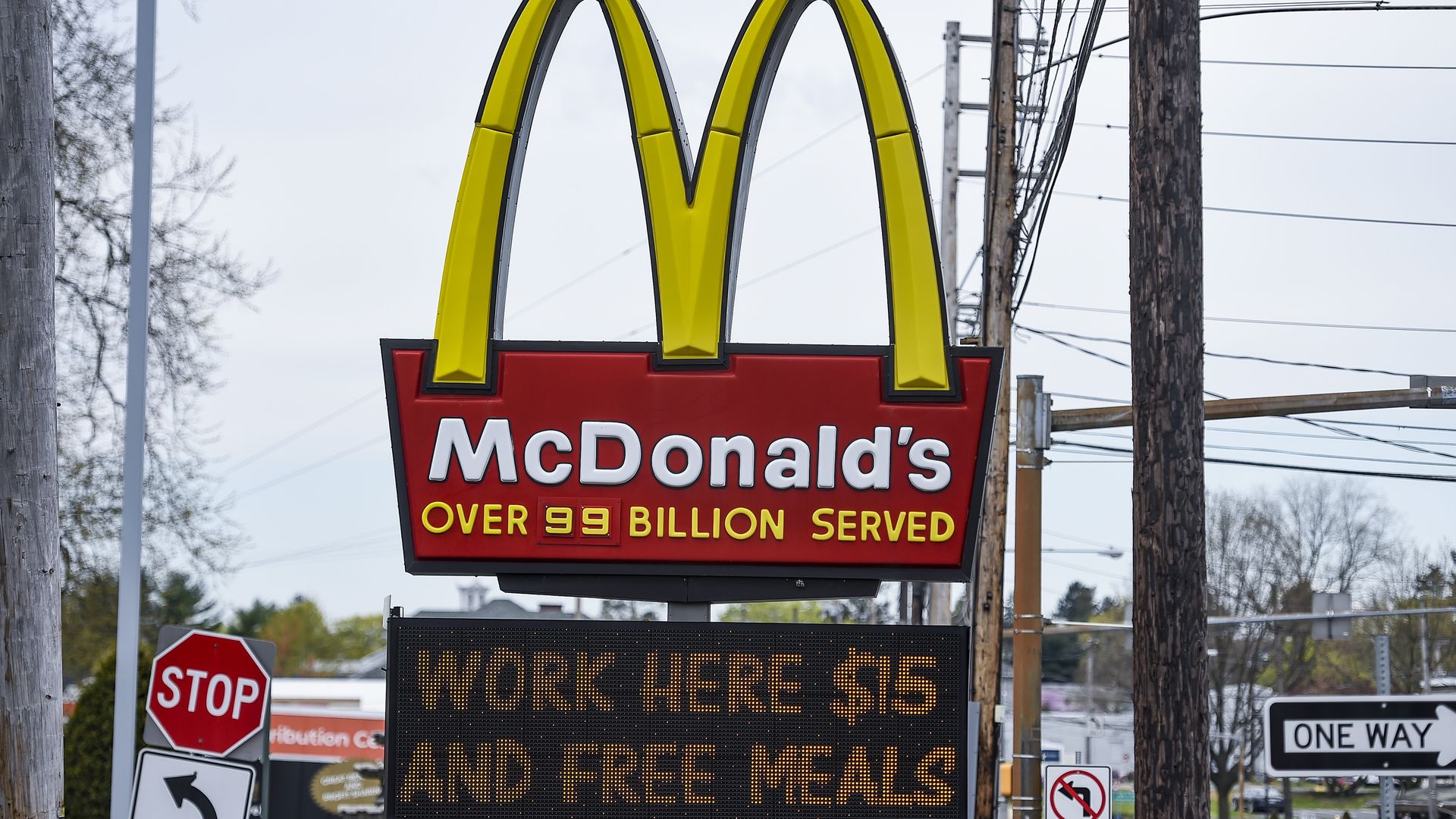 Picture of a McDonald's sign with a sign below it that says "work here $15 and free meals"