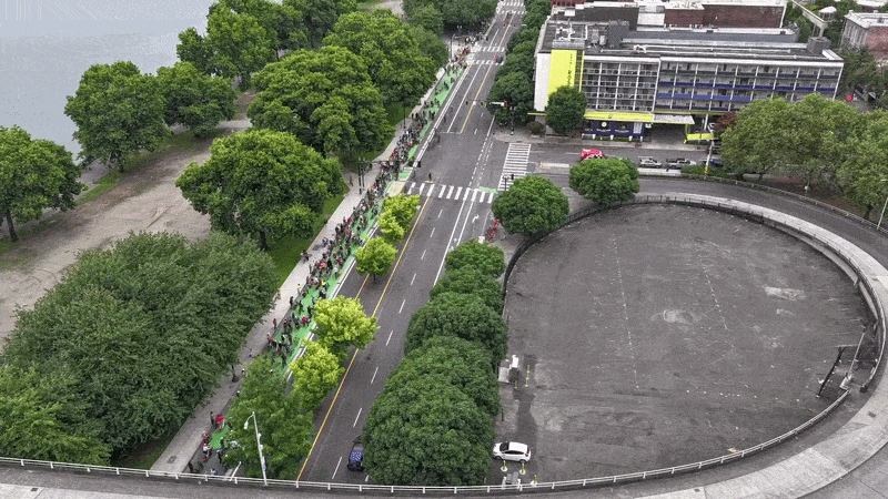 Animated gif shows drone footage of hundreds of people on bicycles lining up along a street next to a river in downtown Portland