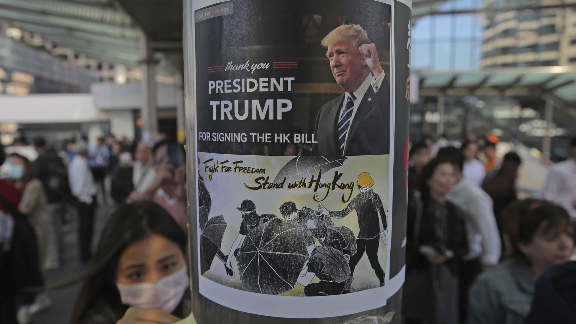 A pro-democracy protester sticks a poster featuring President Trump on a pillar in the Hong Kong financial district today