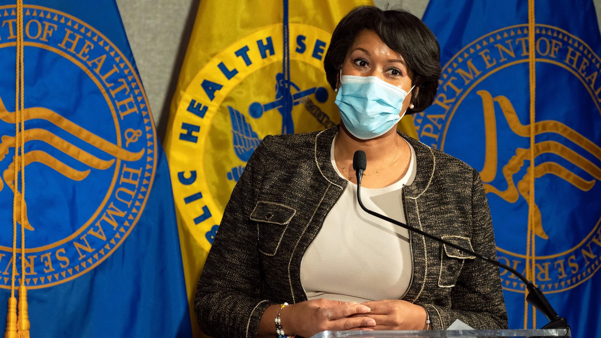 Muriel Bowser wears a face mask while standing in front of a podium