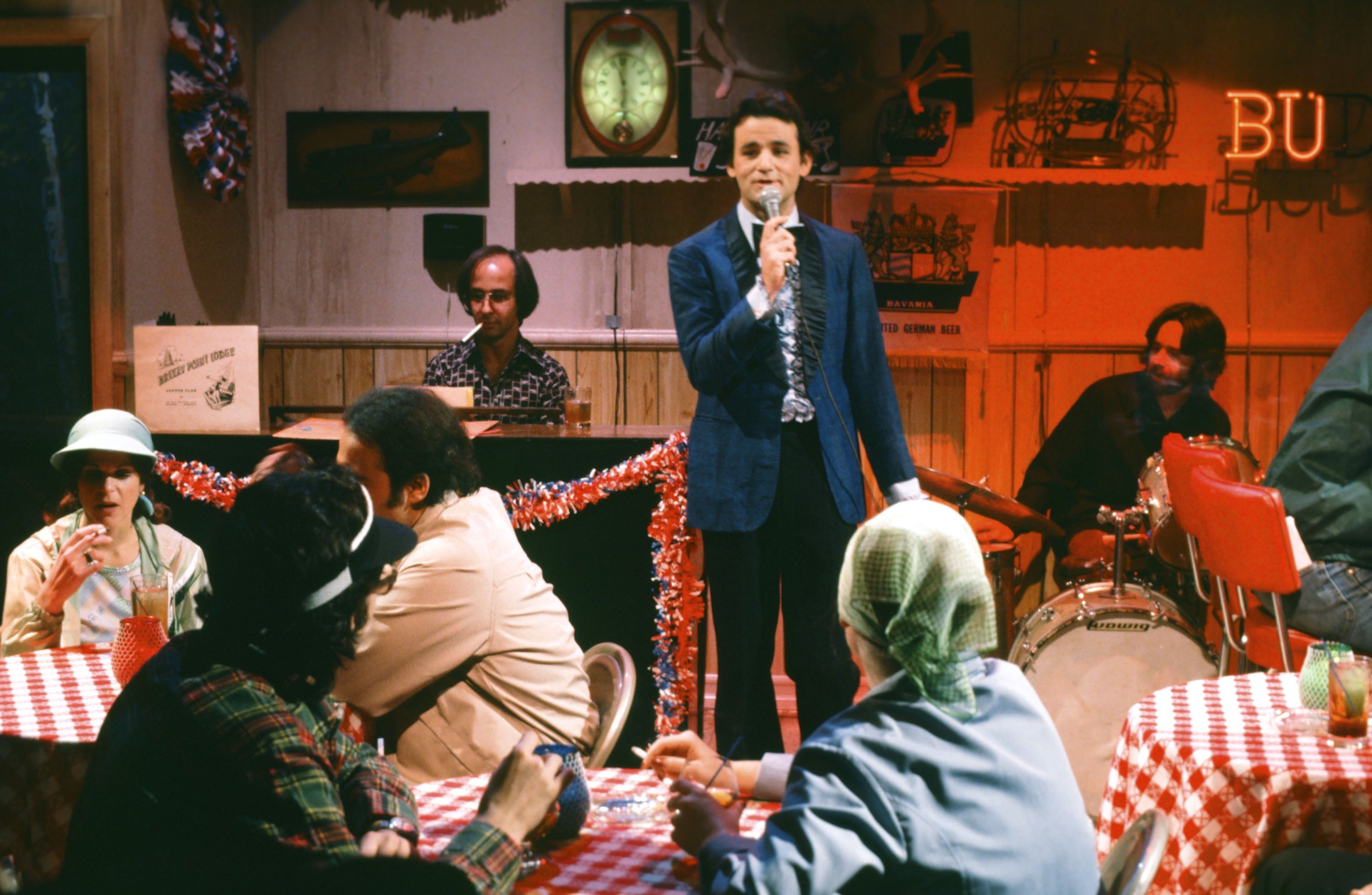Photo of an actor singing at a cafe in a theater scene on stage. 