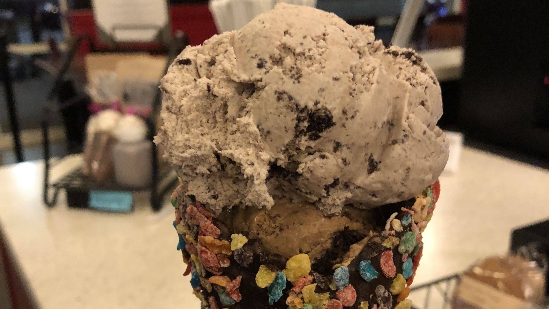 An ice cream cone from JP Licks at Brigham Circle: It's got waffle cone dipped with chocolate and fruity pebbles and two scoops of cookies and cream anad coffee cookies and cream ice cream.