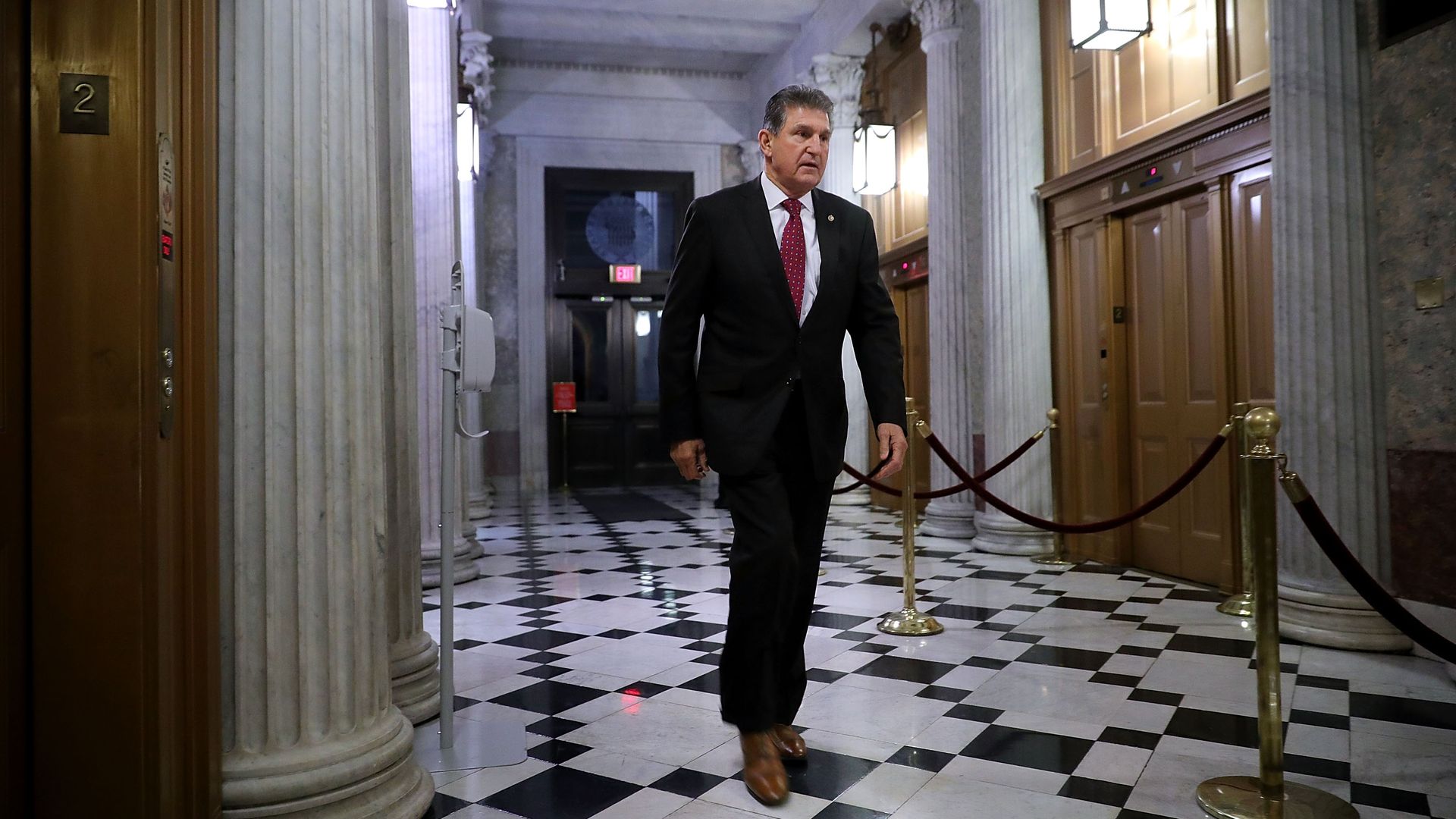 Joe Manchin walks down a hallway on the Hill