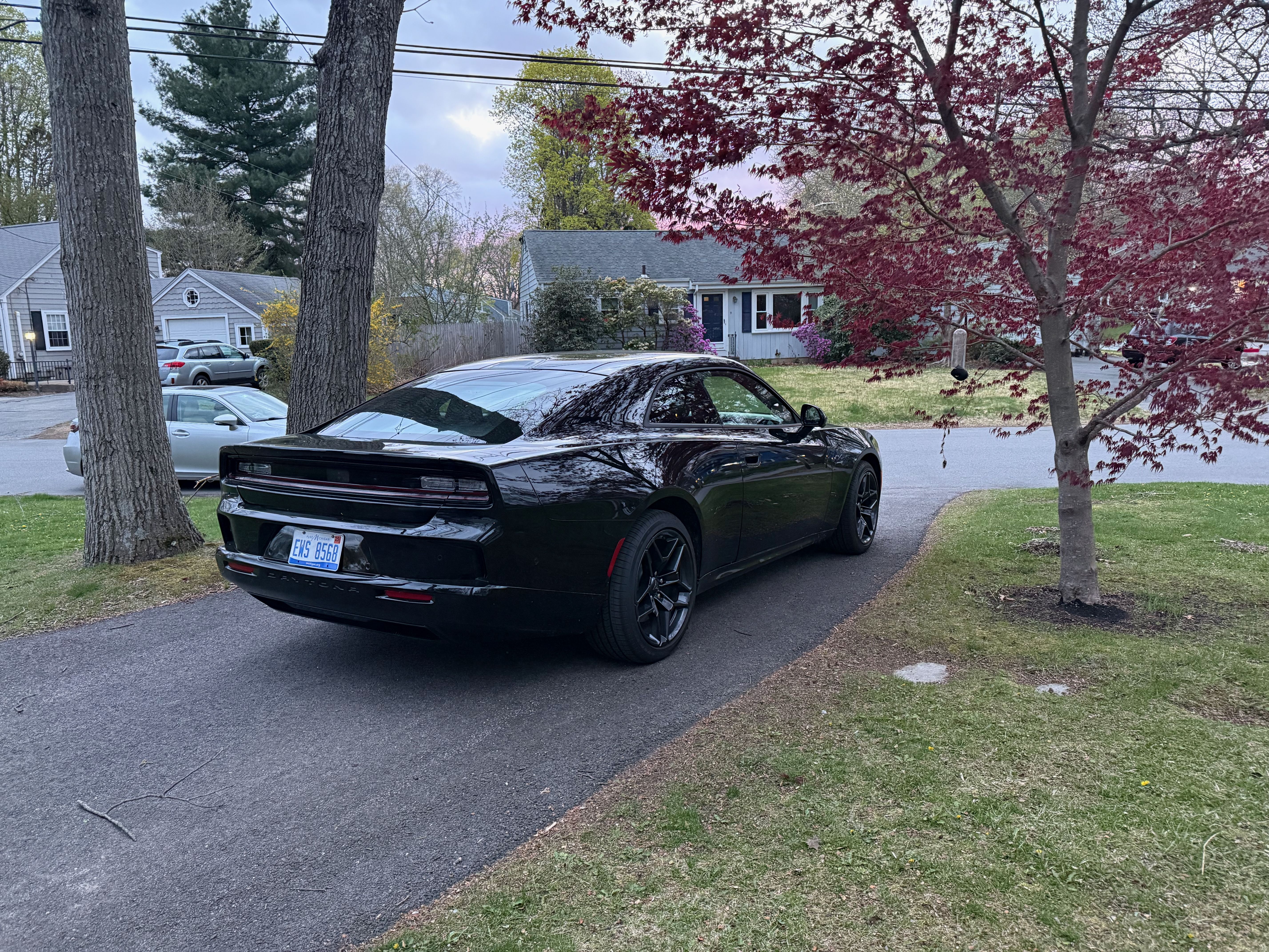 A black Dodge Charger Daytona EV, parked in a suburban driveway.