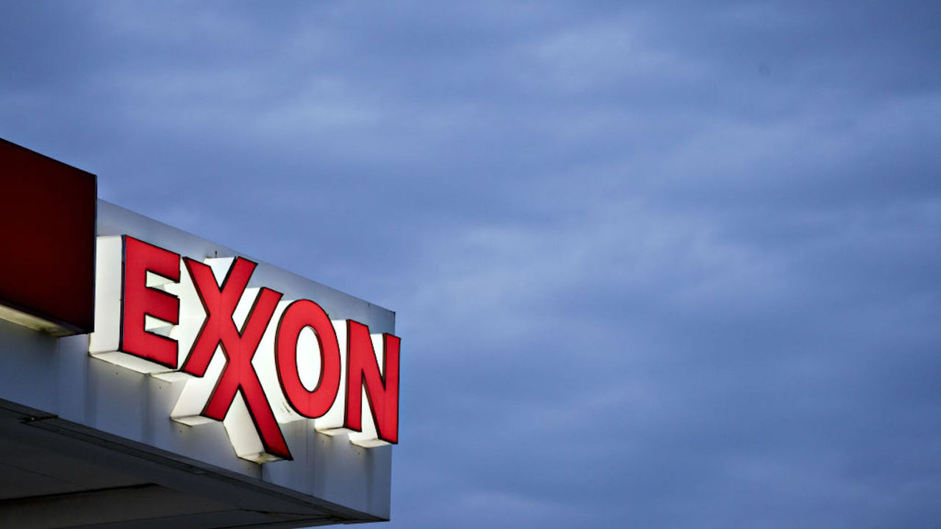 Photo of an Exxon station logo against a cloudy sky