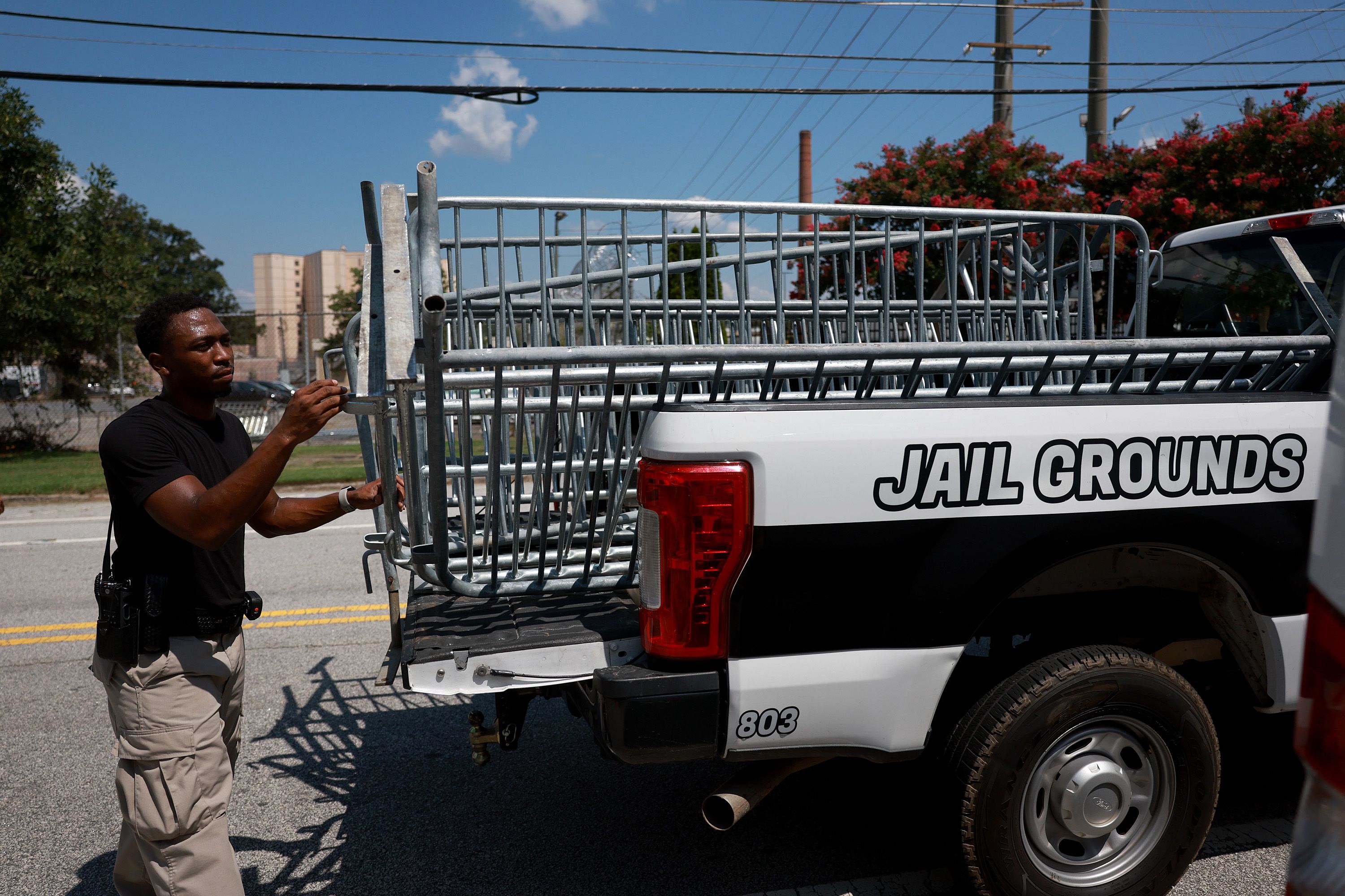 A sheriff's officer helps put up fencing near an entrance to the Fulton County (Ga.) Jail, where former President Trump is expected to be booked late this week.