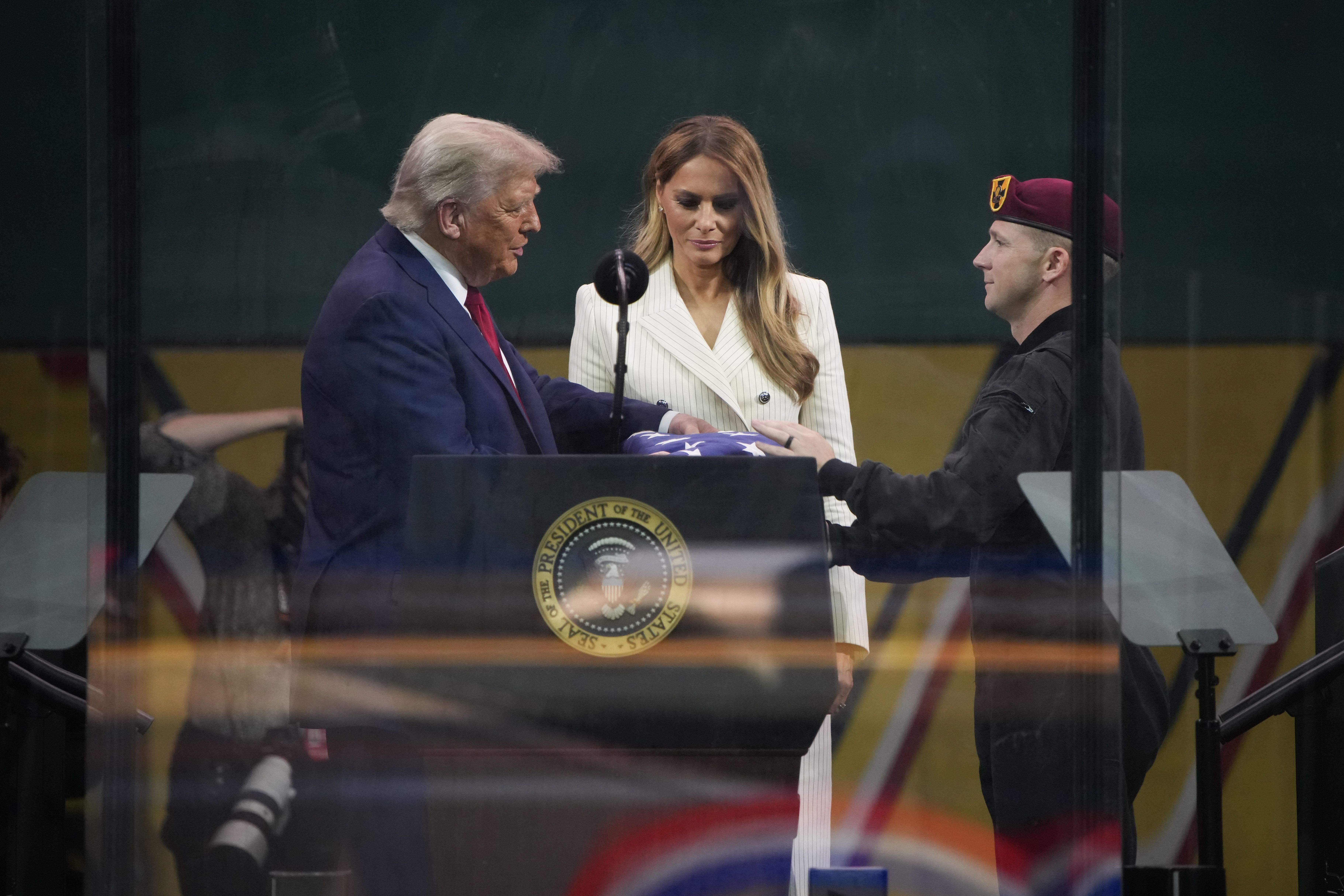  President  Trump and first lady Melania Trump stand together as he is given an American flag by a member of the U.S. Army parachute team, also known as the Golden Knights, at the end of the U.S Army parade on June 14, 2025 in Washington, DC. 