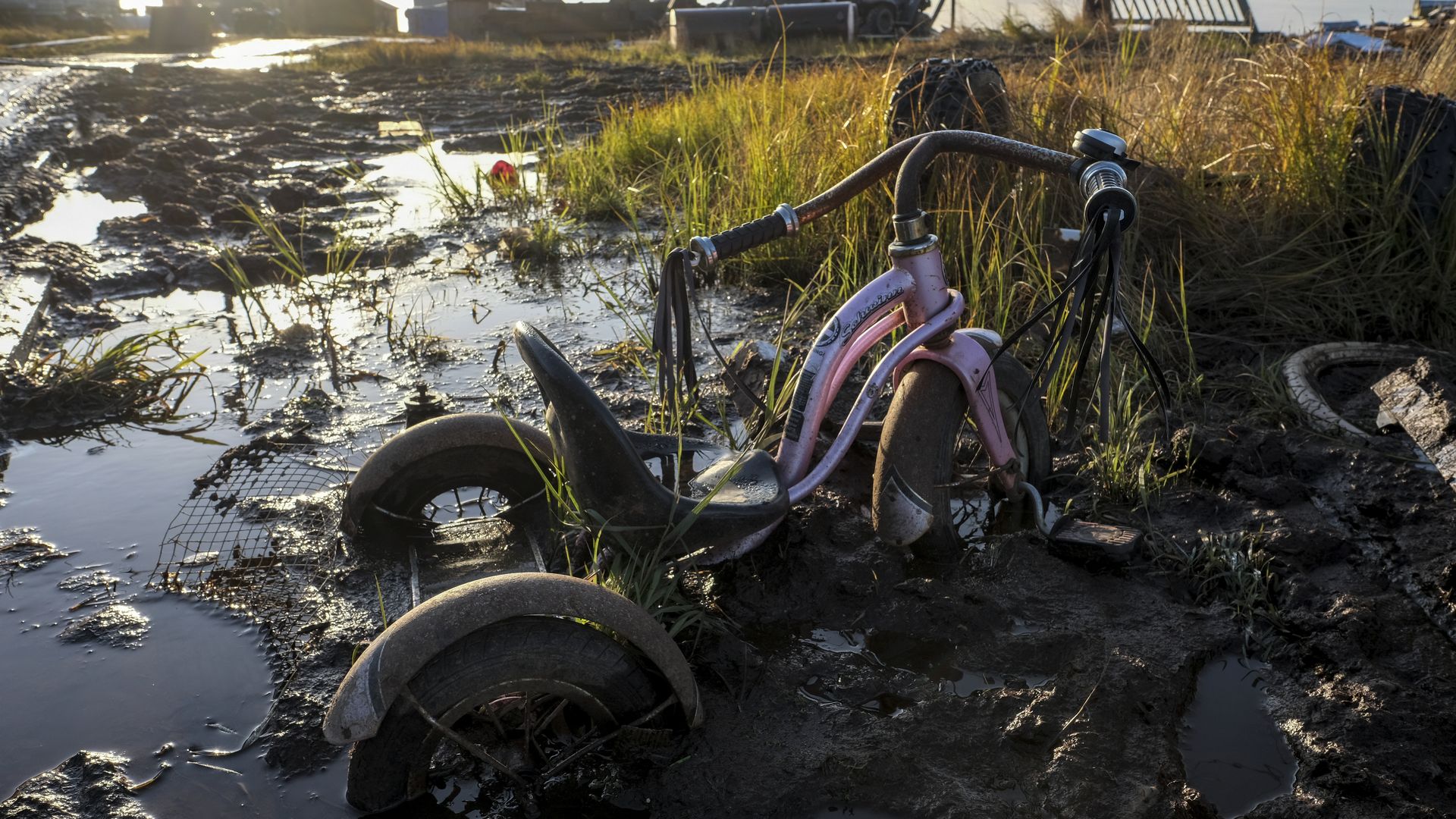 Photo of a child's tricycle sinking into mud