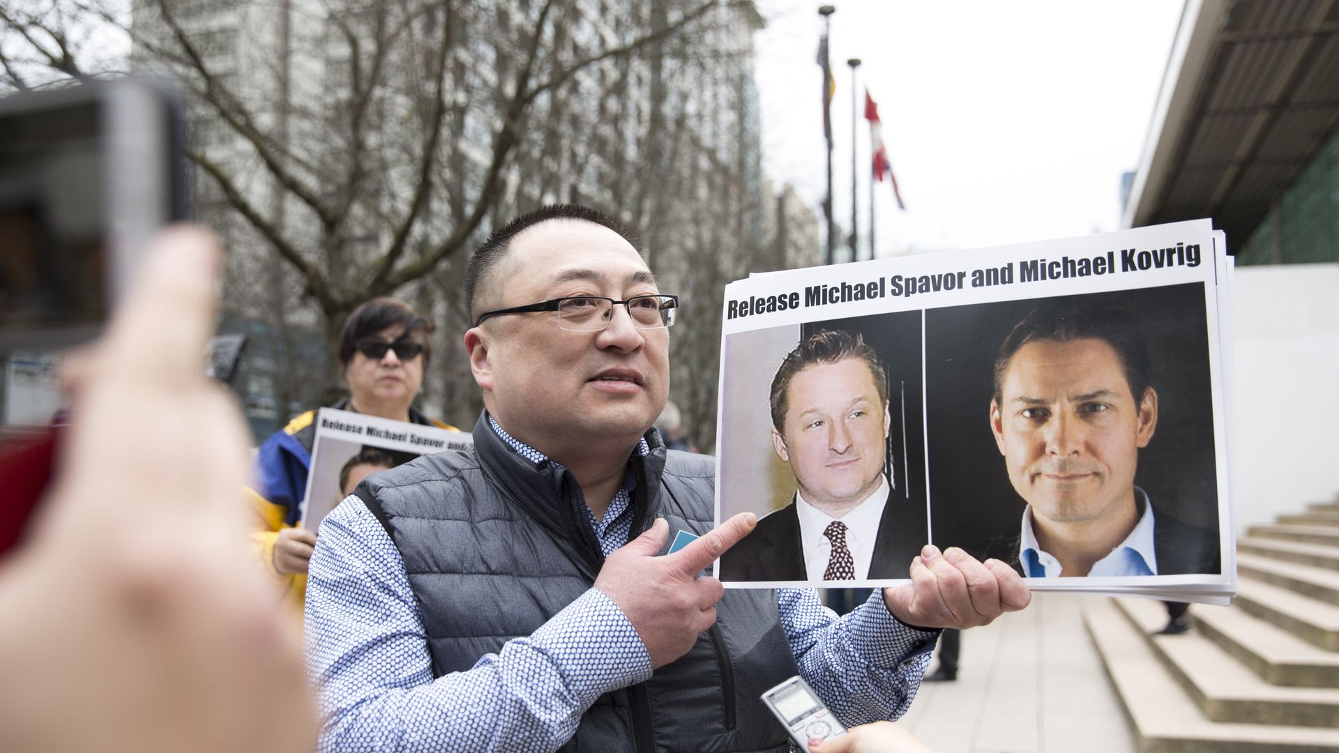 Louis Huang of Vancouver Freedom and Democracy for China holds photos of Canadians Michael Spavor and Michael Kovrig.