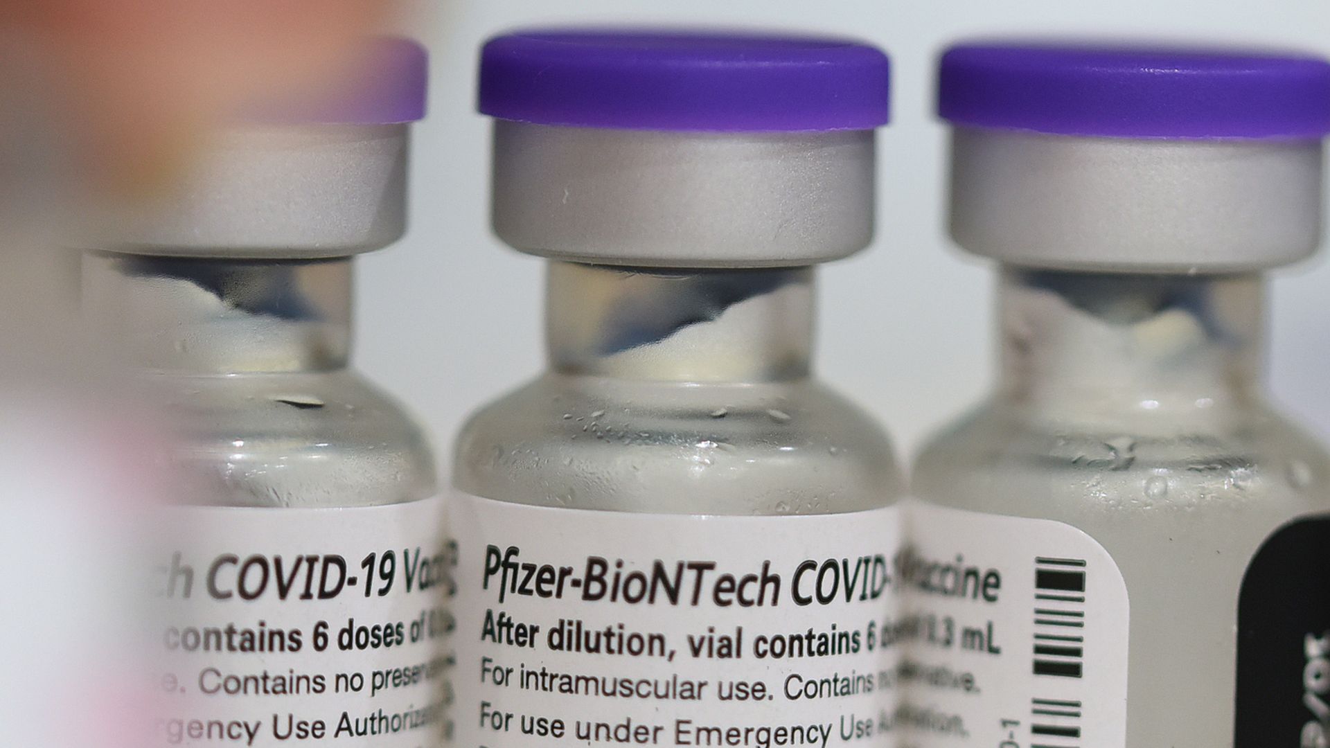 A close-up shot of three vials of the Pfizer-BioNTech COVID-19 vaccine.
