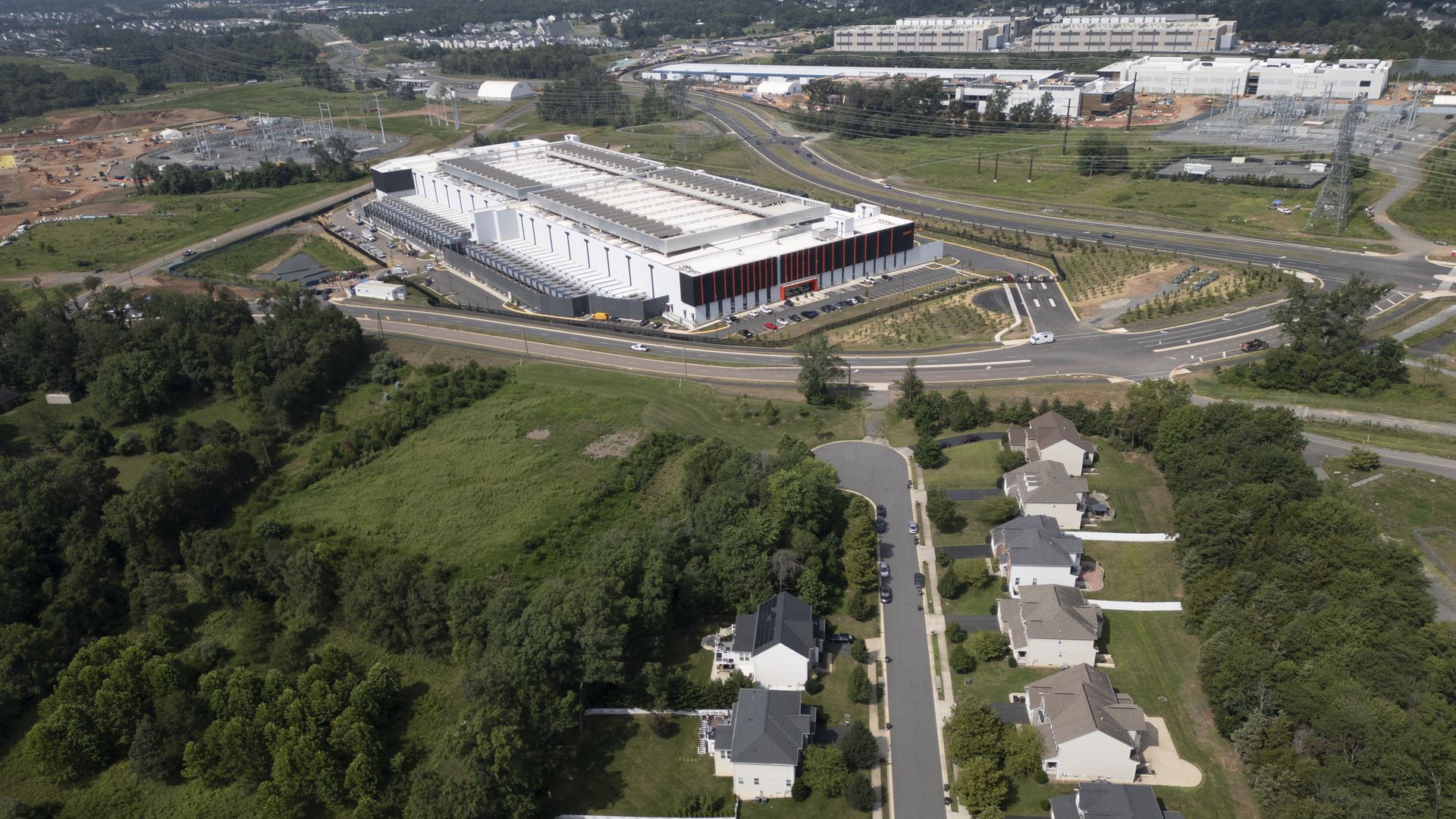 An aerial view of a data center in Ashburn, Virginia, with single-family homes in the foreground near a large data center facility 