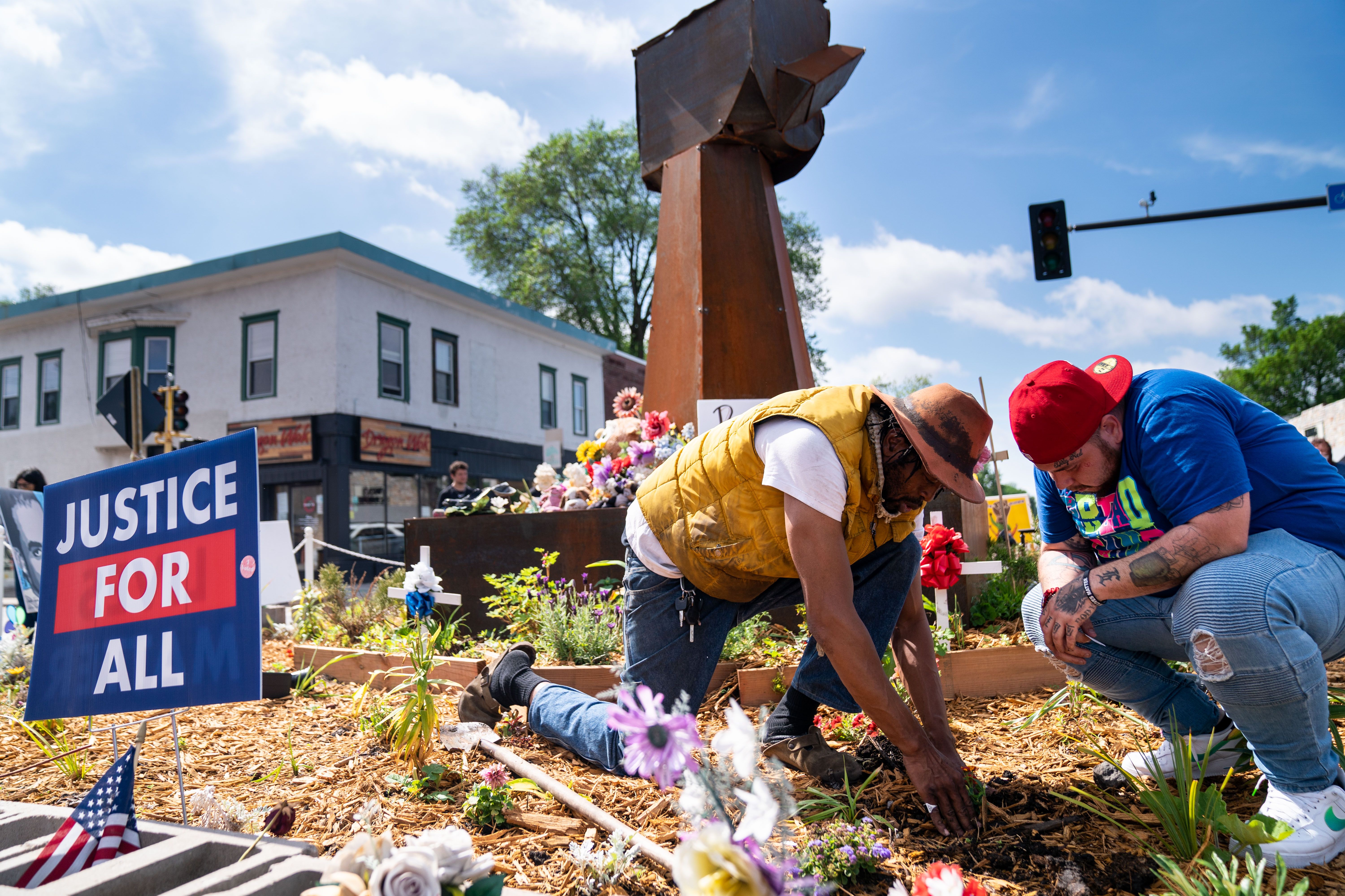 Jay Webb and Damik Wright, the brother of Daunte Wright, plant flowers near the fist sculpture in the center of George Floyd Memorial Square Square on Tuesday, May 25, 2021 in Minneapolis