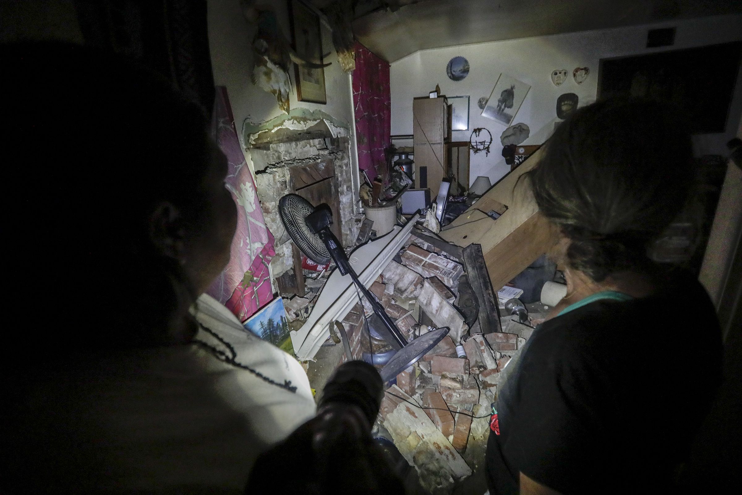 This image shows a flashlight being shown on the inside of a house in complete disarray. 