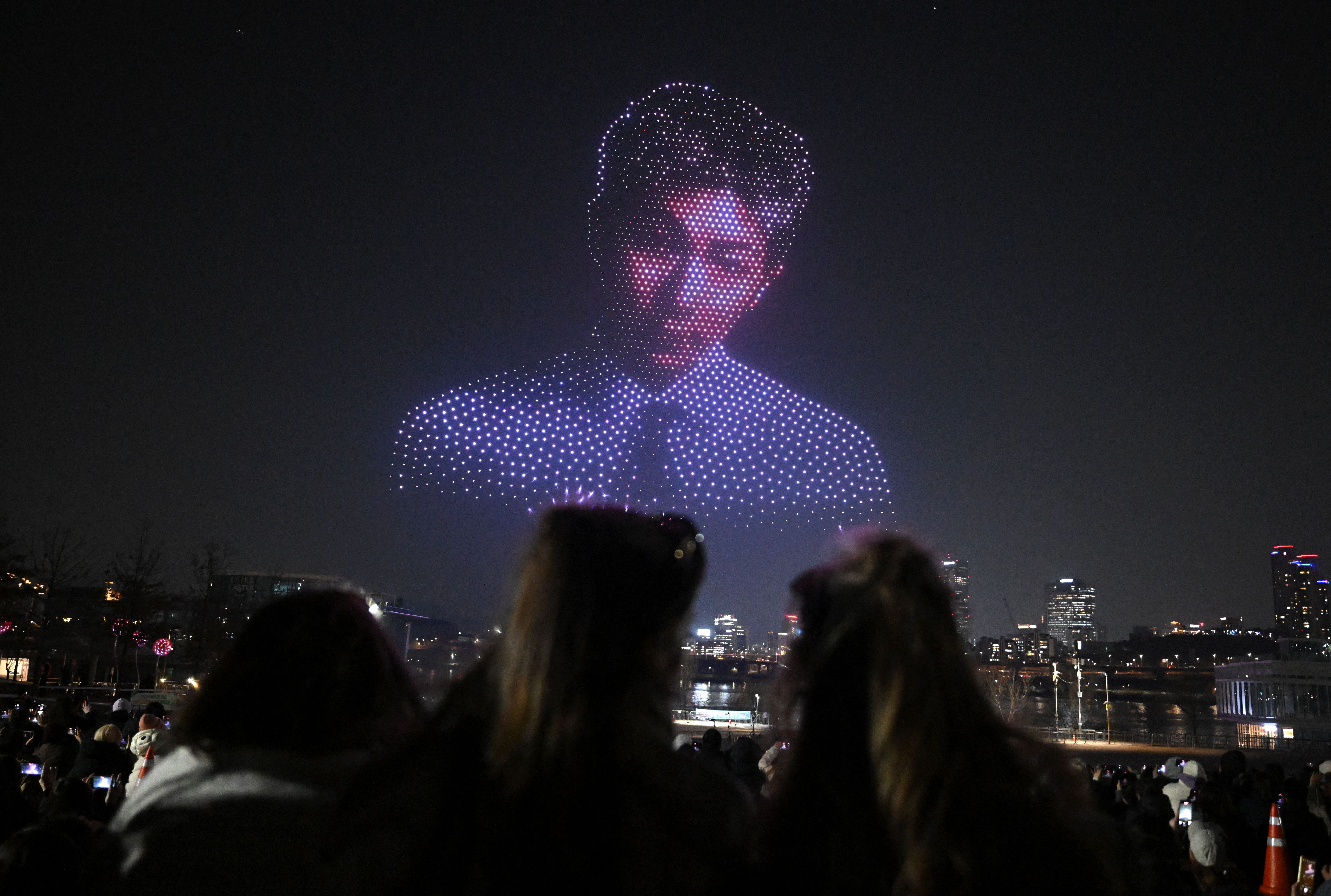 Illuminated drones create a portrait of BTS member RM in the night sky over a riverside park in Seoul.