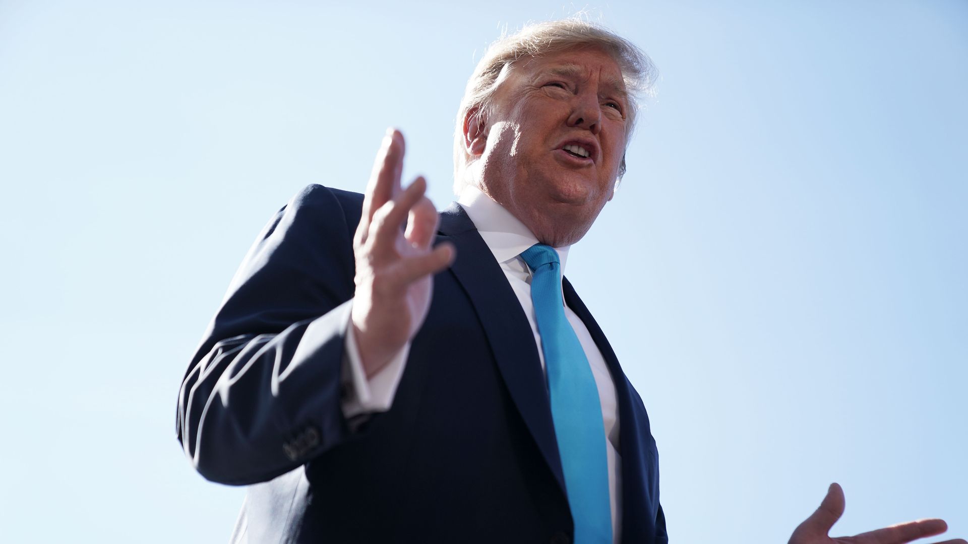 In this image, Trump talks and gestures with his hands.