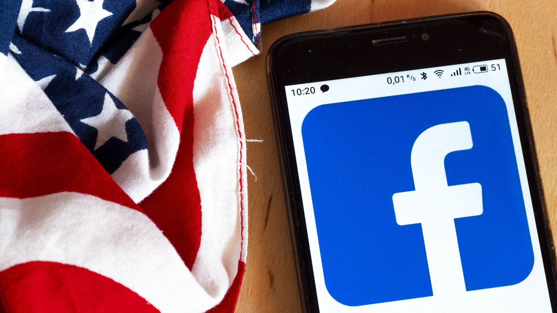 A photo of a smartphone displaying the Facebook logo with an American flag behind it