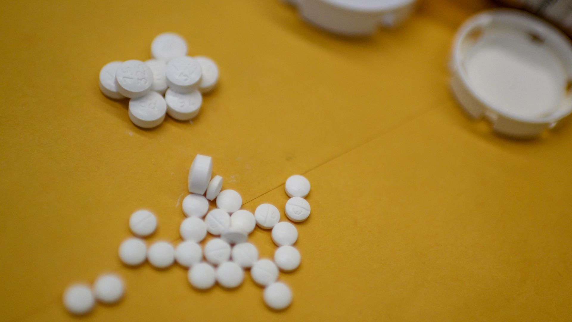 Pills scattered on a yellow surface.