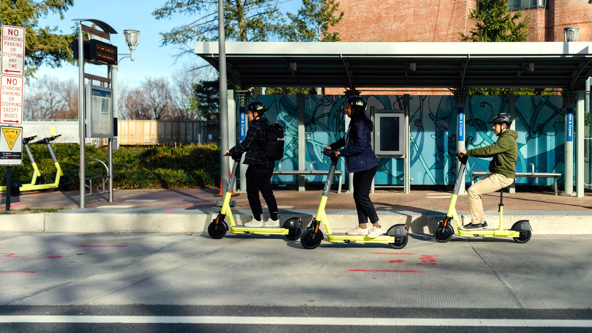 Three riders on e-scooters on a city street.