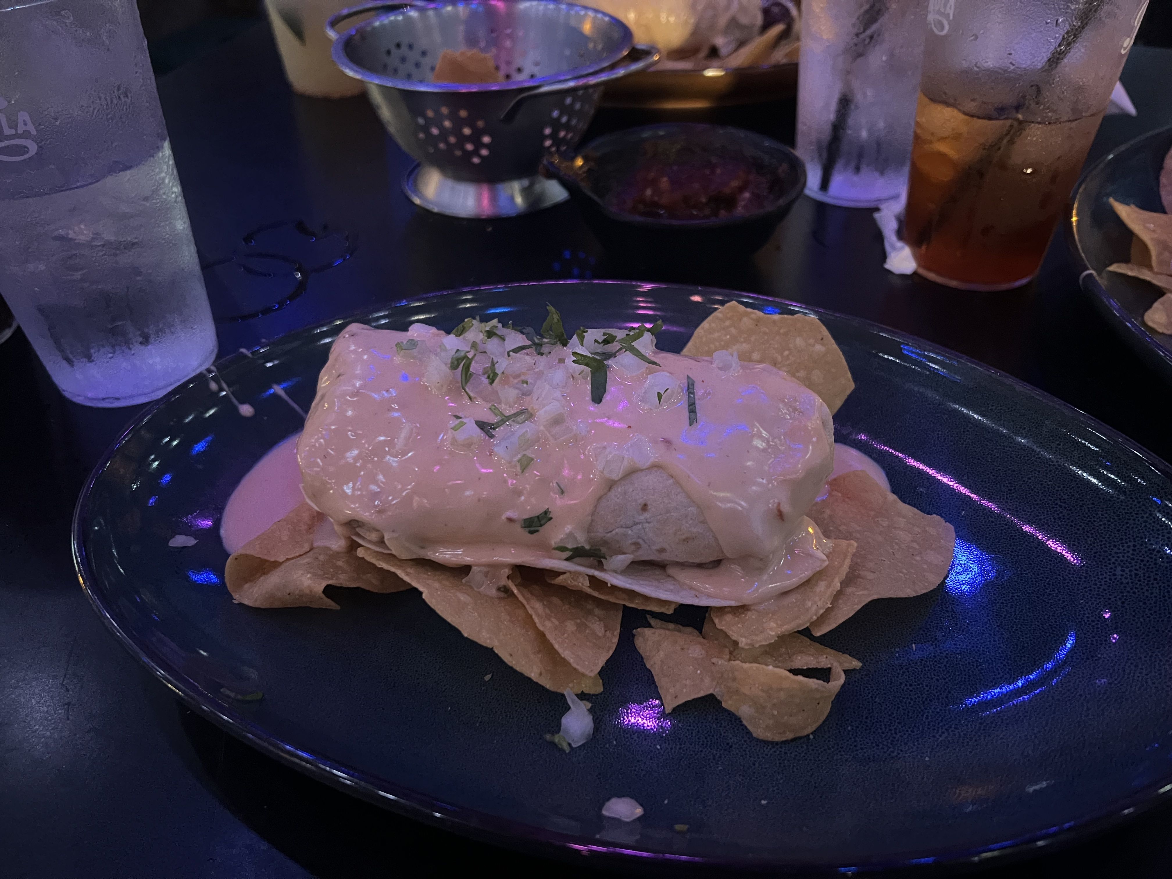 large burrito smothered in queso on a bed of cips