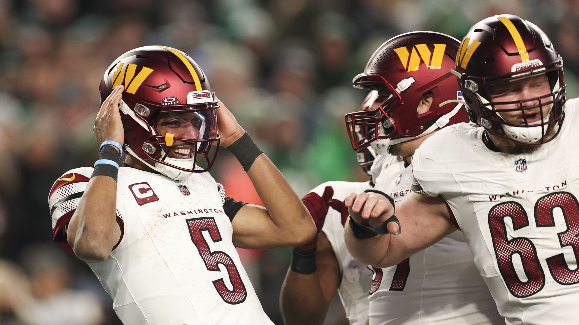 Jayden Daniels celebrates with other Commanders players on the field.
