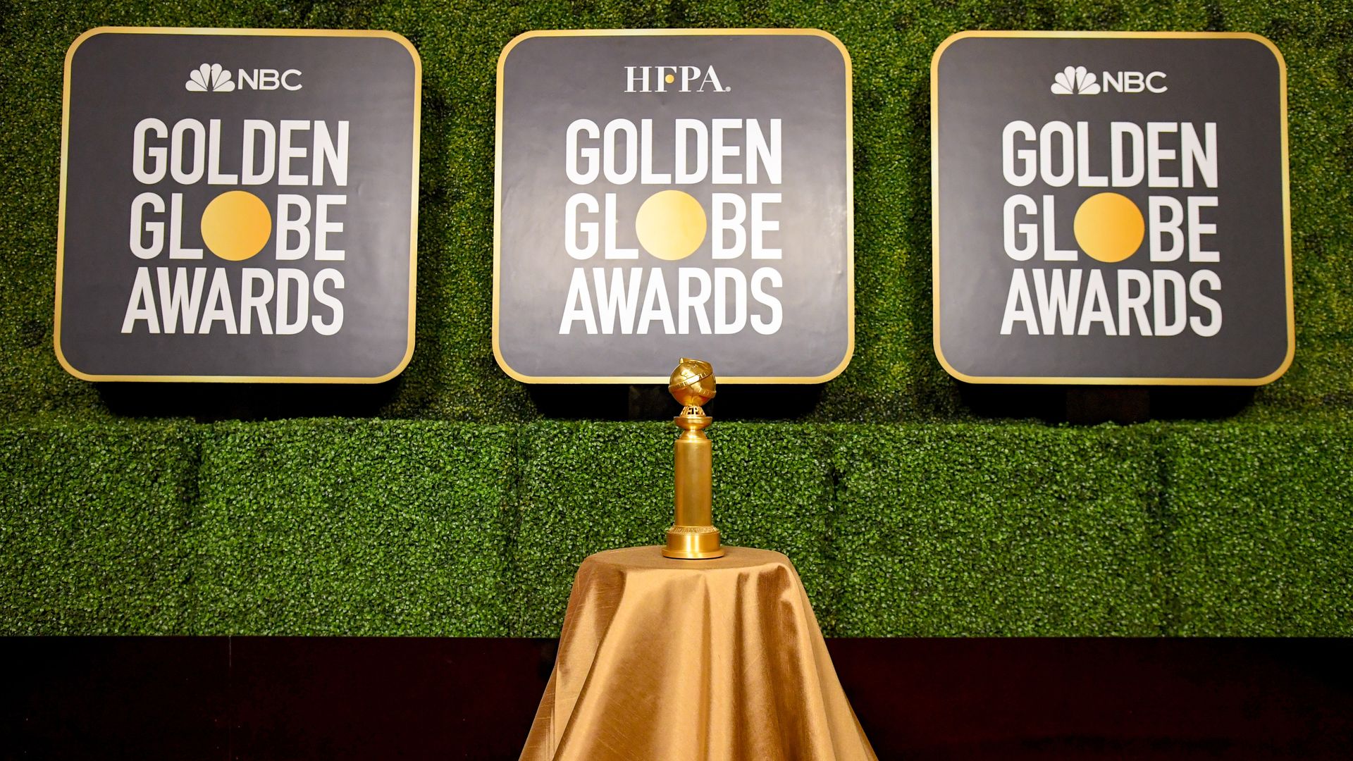 A Golden Globes statue sits in front of signs announcing the Golden Globe Awards