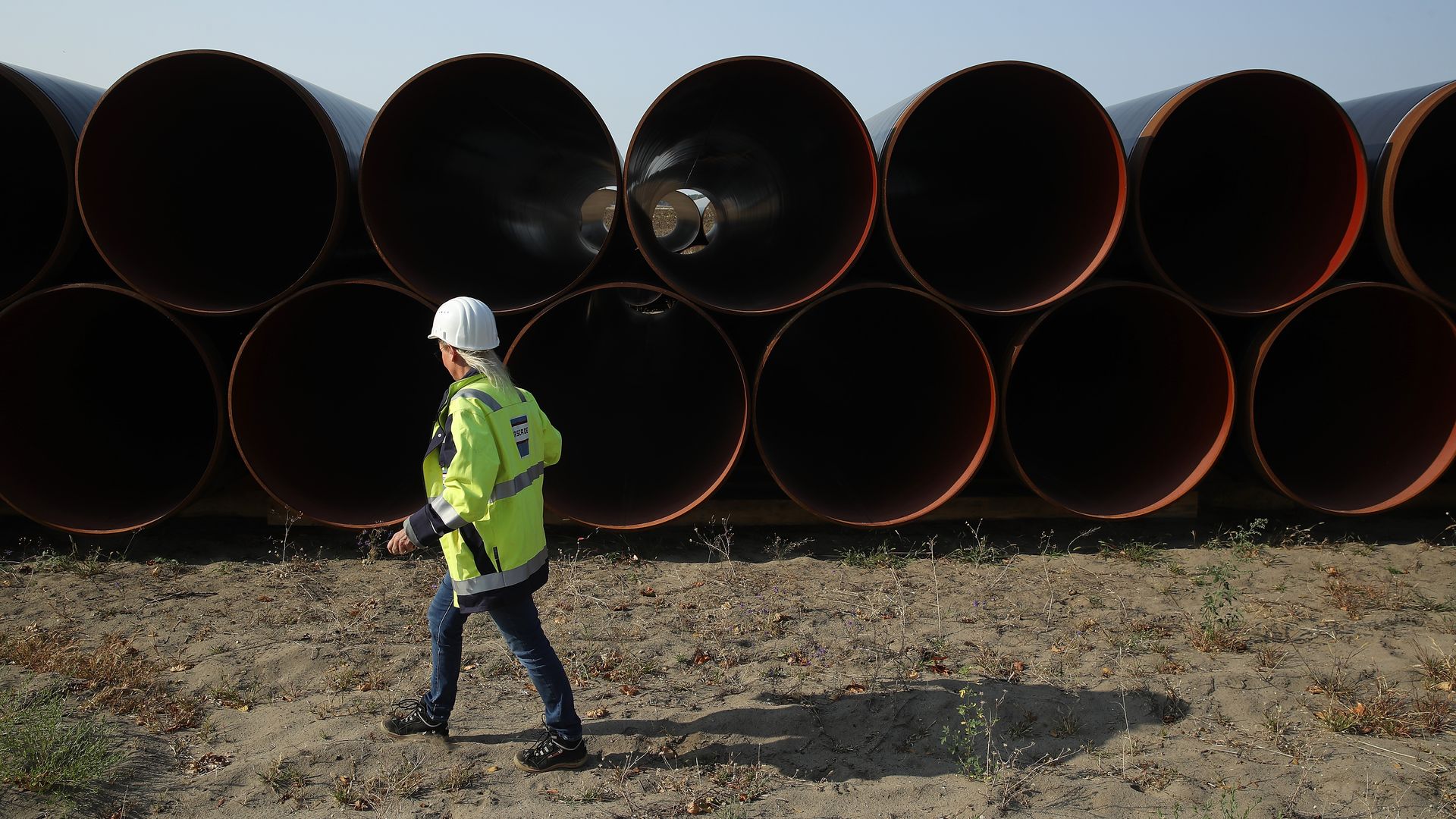 An employee of GASCADE Gastransport GmbH walks among sections of steel pipe stacked ahead of construction of the Eugal natural gas pipeline
