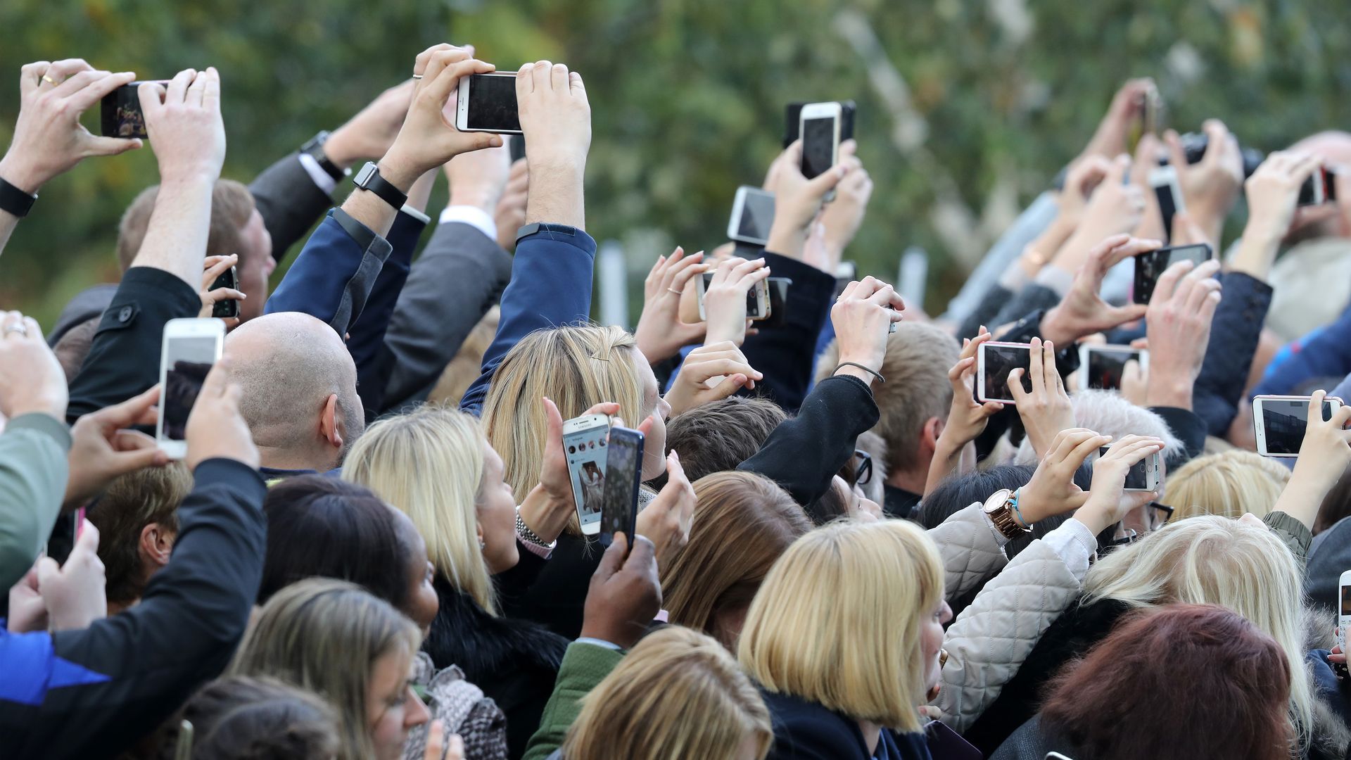 A group of people use cell phones to take pictures of Prince William