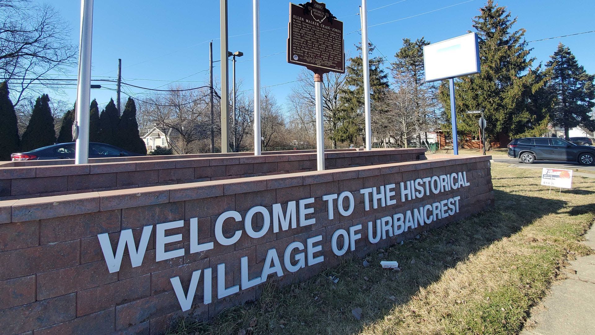 A historical marker in front of a sign reading "Welcome to the Historical Village of Urbancrest."