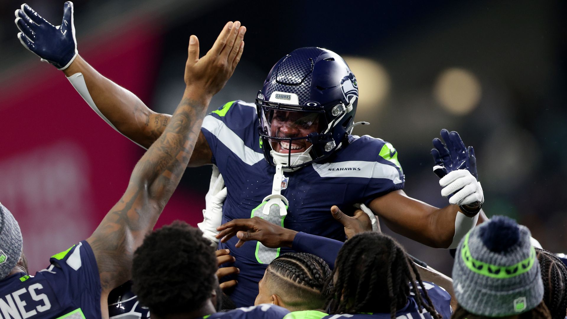 A football player is lifted by teammates after scoring a touchdown. 