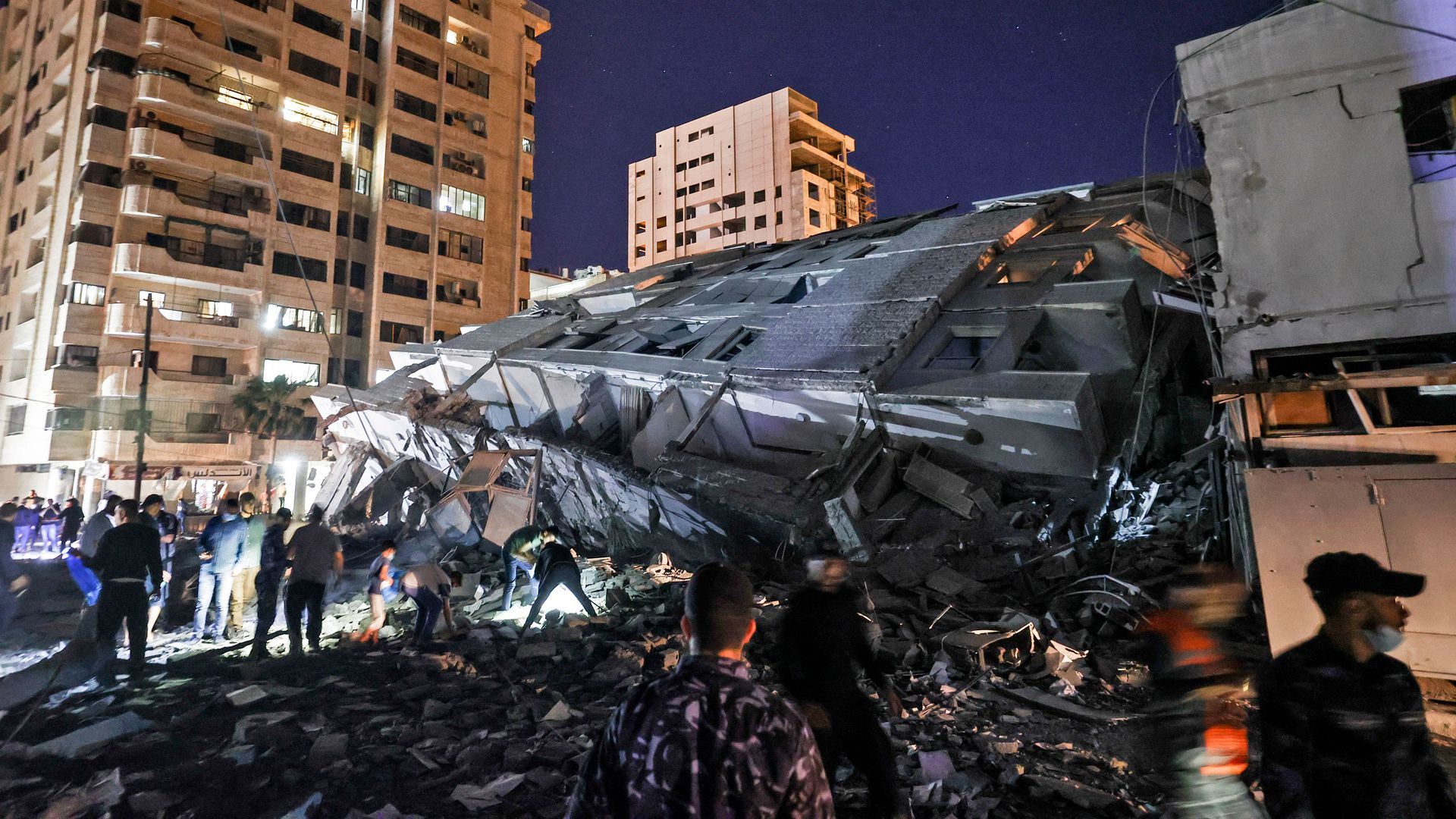 People gather at the site of a collapsed building in the aftermath of Israeli air strikes on Gaza City on May 11.