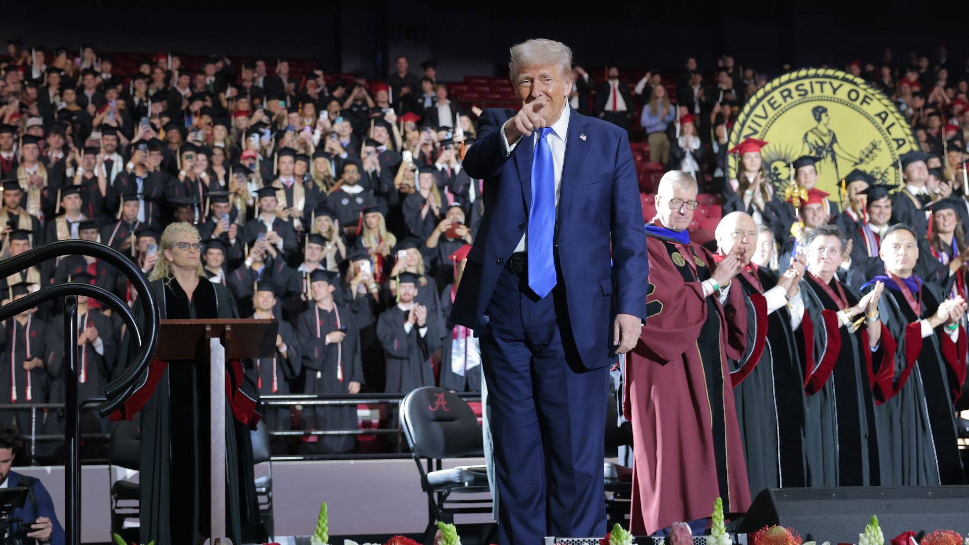 Trump points at audience from a graduation stage