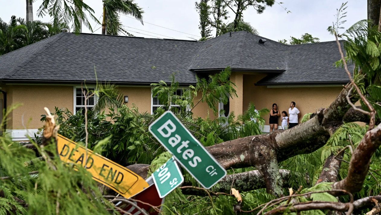 Oscar Garcia (R) with his family stands outside his house after it was struck by a reported tornado in Fort Myers, Florida, on Oct. 9 as Hurricane Milton approaches. 