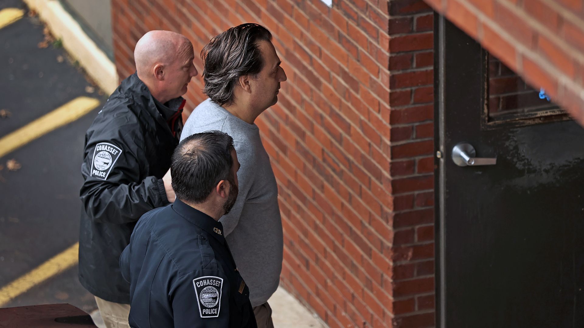 Two police officers lead Brian Walshe in handcuffs into Quincy District Court to be arraigned on murder charges.