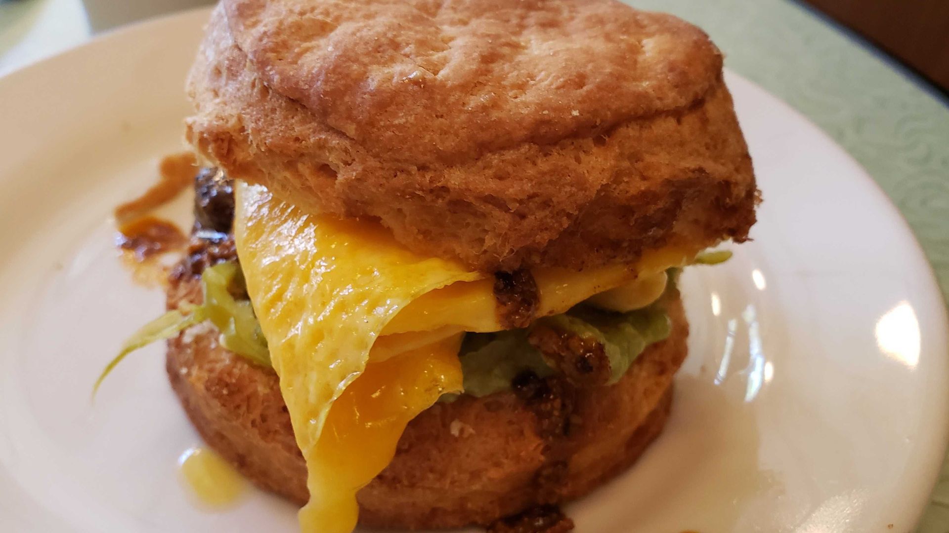 An egg breakfast sandwich with sriracha oozing out.