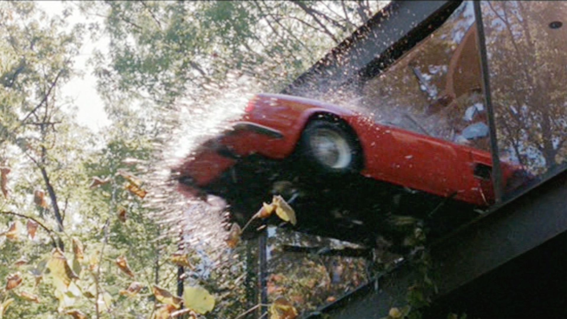 A red sports car smashing through a glass window