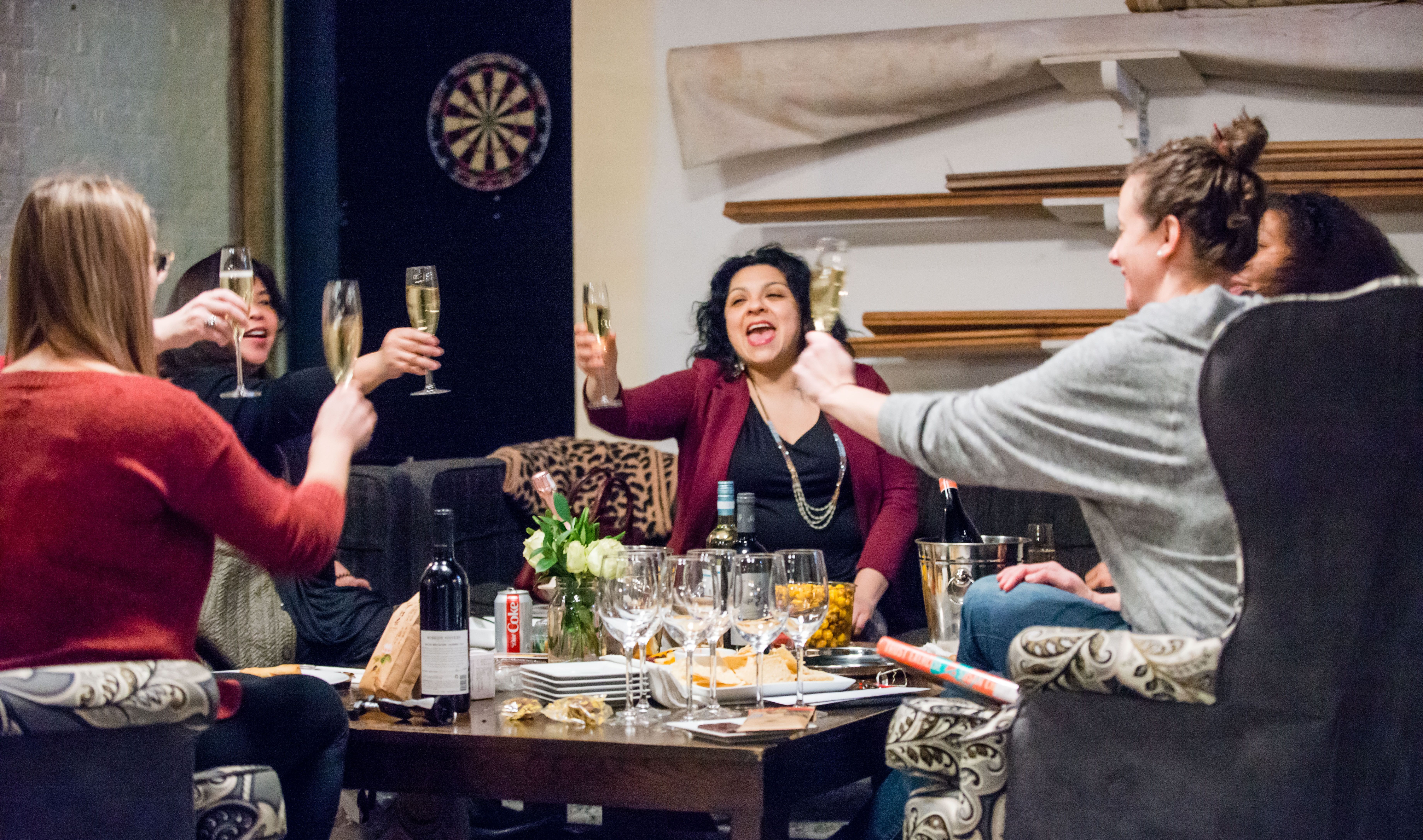 Five women raise glasses of champagne.
