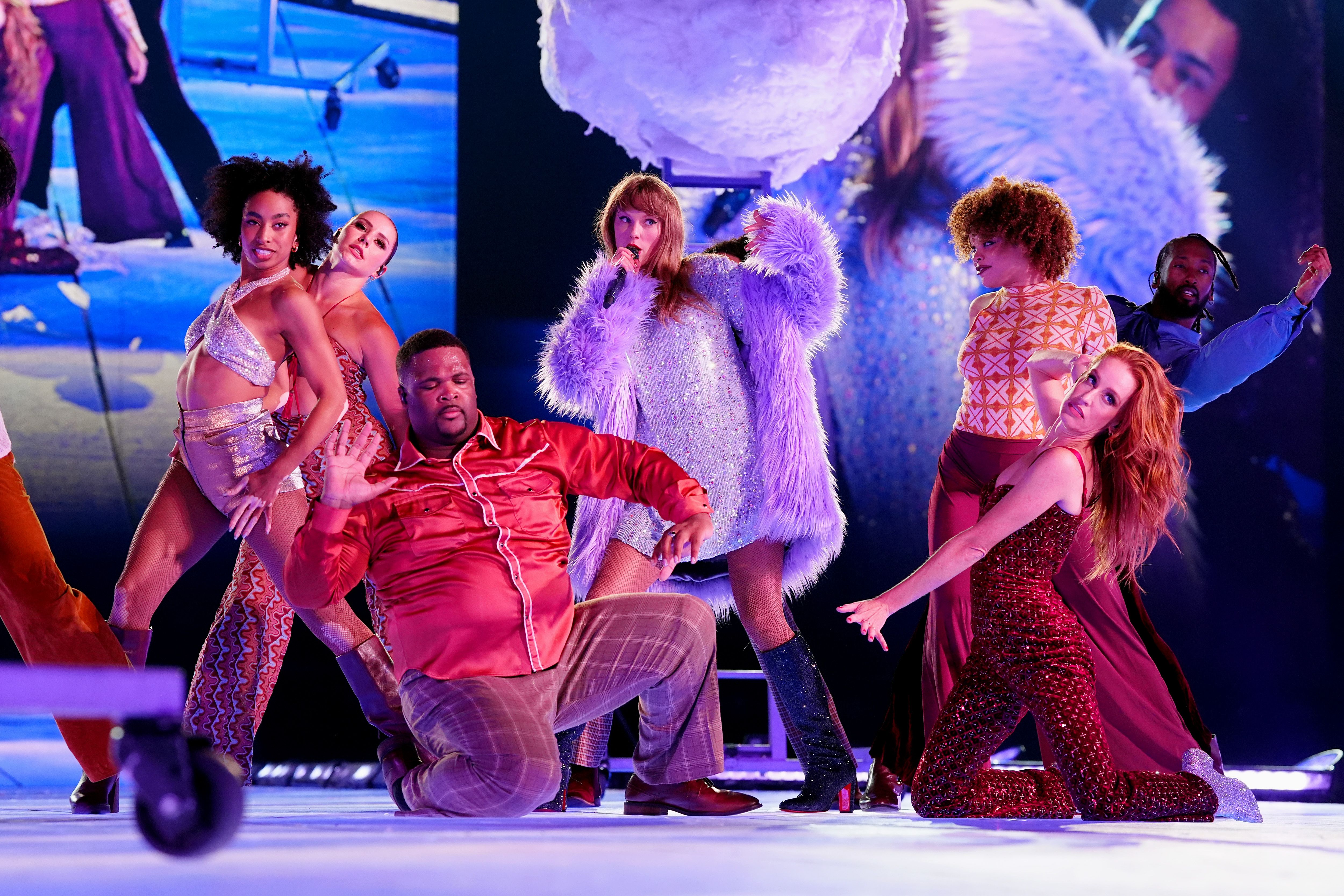 Photo shows Taylor Swift on stage with dancers.