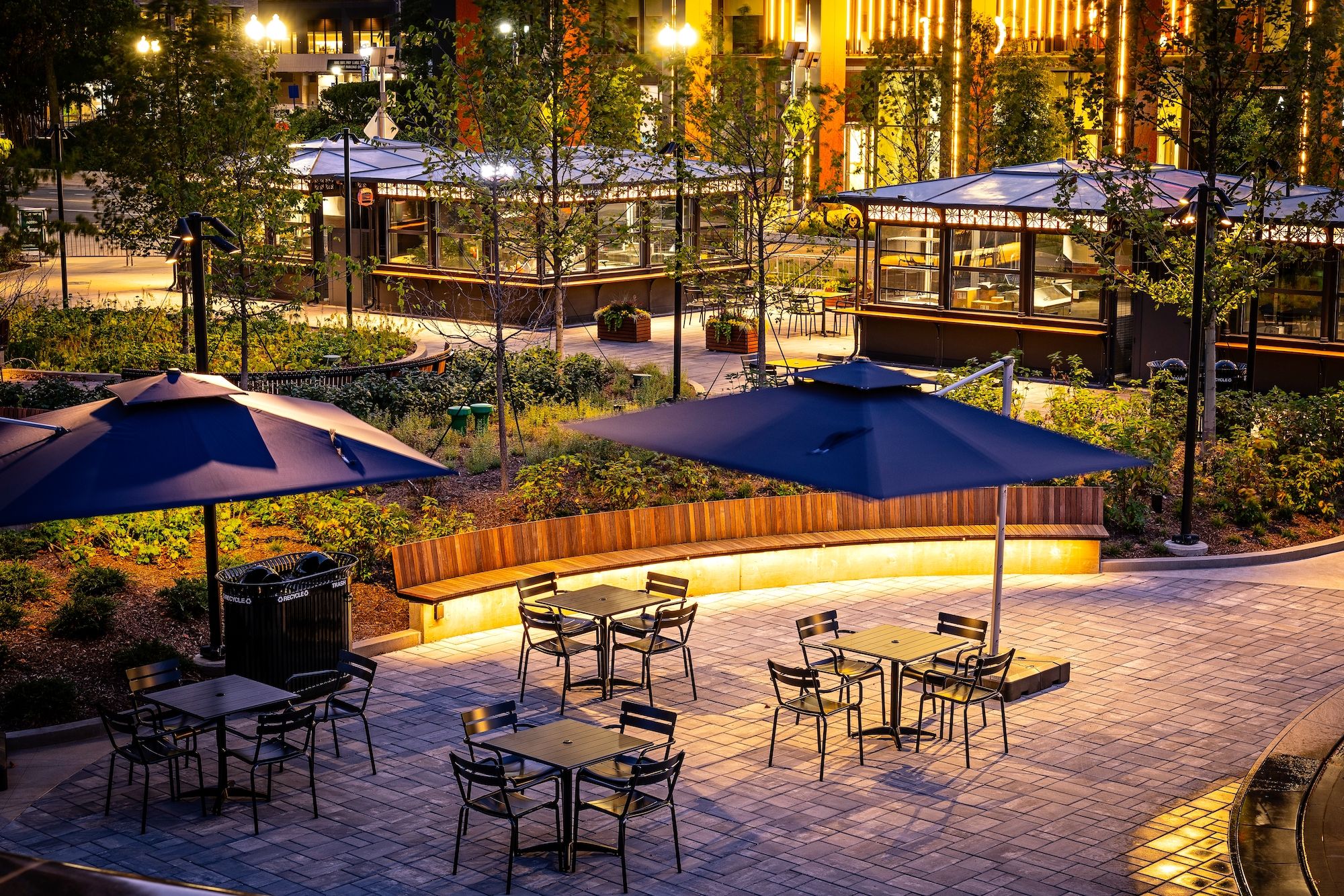 An outdoor park lit up at night with chairs, umbrellas, and food kiosks